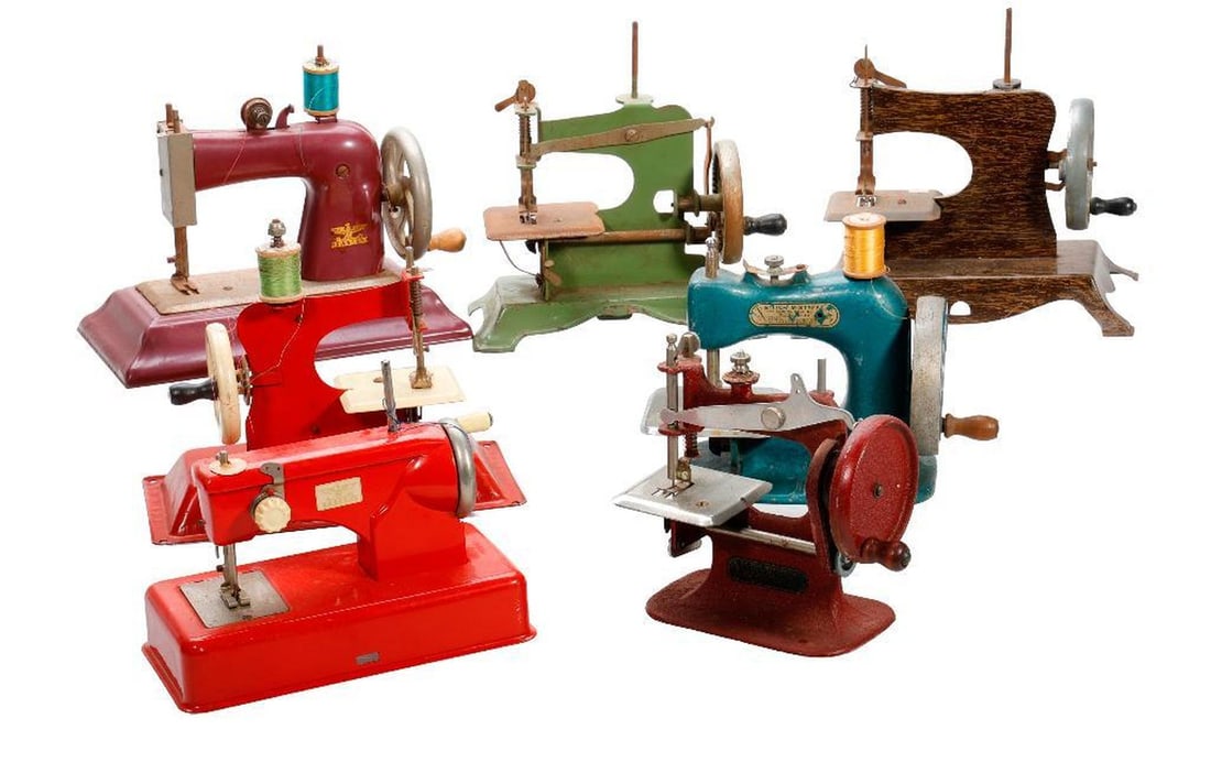 Seven Vintage Miniature Sewing Machines: Both cast iron and litho tin bodied machines, including (2) Stitch Mistress Juniors (a red no model # and a green Model #49) and a red German Casige, the largest 7.5"h x 8.75"w x 5"d