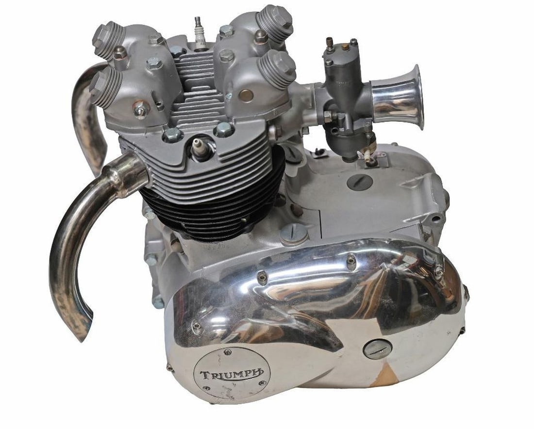 Triumph Parallel-Twin Motorcycle Engine: Dating to the 1970s. Features a silver finished body with a stamped 932 Series AMAL Concentric Mk1 carburetor with attached velocity stack/air trumpet, connects to cylinder head intact