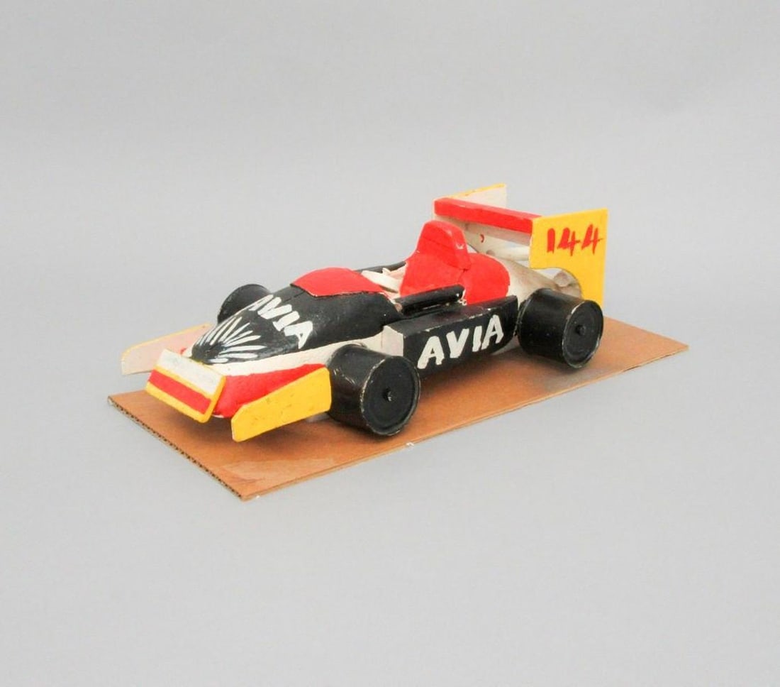 Avia Race Car: Handmade painted wooden car; black, red, yellow exterior with black wheels; "Avia" painted on sides;144, painted on rear fin. Dimensions: 4 1/2 x 7 x 14 1/2 inches (11.4 x 17.8 x 36.8 cm).