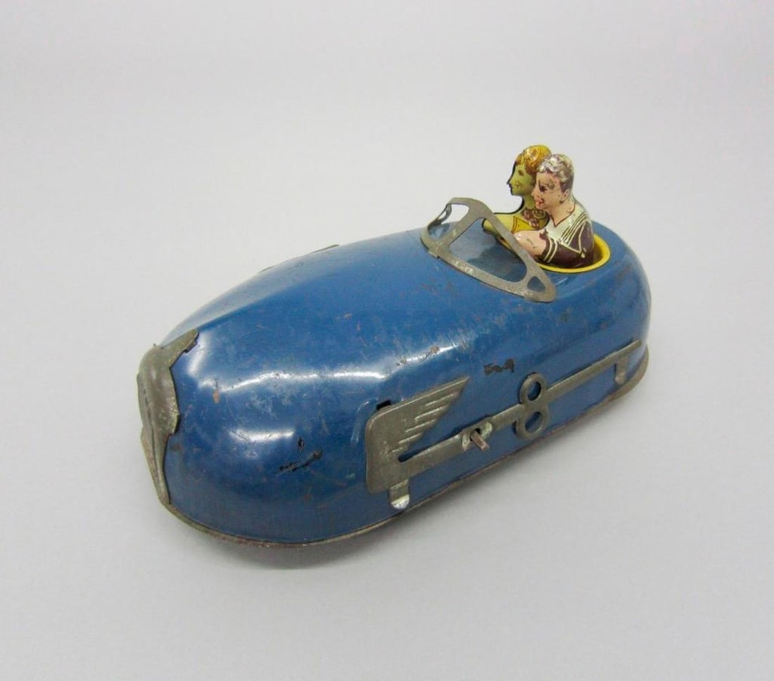 Vintage Bumper Car: Blue, key-wind toy bumper car with two passengers; stylized "8" and wings on sides. Dimensions: 4.75" x 9" x 5" (12.1 x 22.9 x 12.7 cm). Condition: Scattered abrasions and scratches throughout.