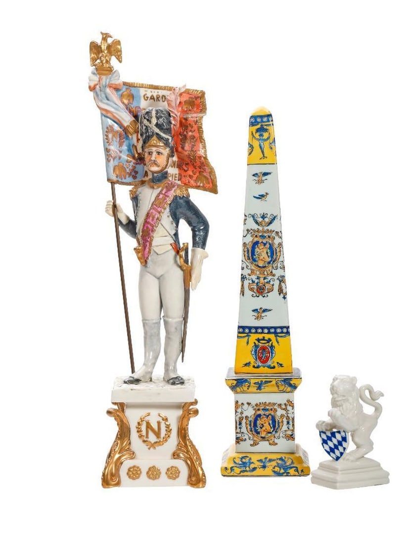 Italian Capo Di Monte Style Porcelain Figure of A Napoleonic Officer: The figure of officer holding a French flag surmounted by an eagle with out swept wings, modeled on a plinth base with a gilt initial "N" in laurel leaf surround 15"h; together with a Nymphenburg 