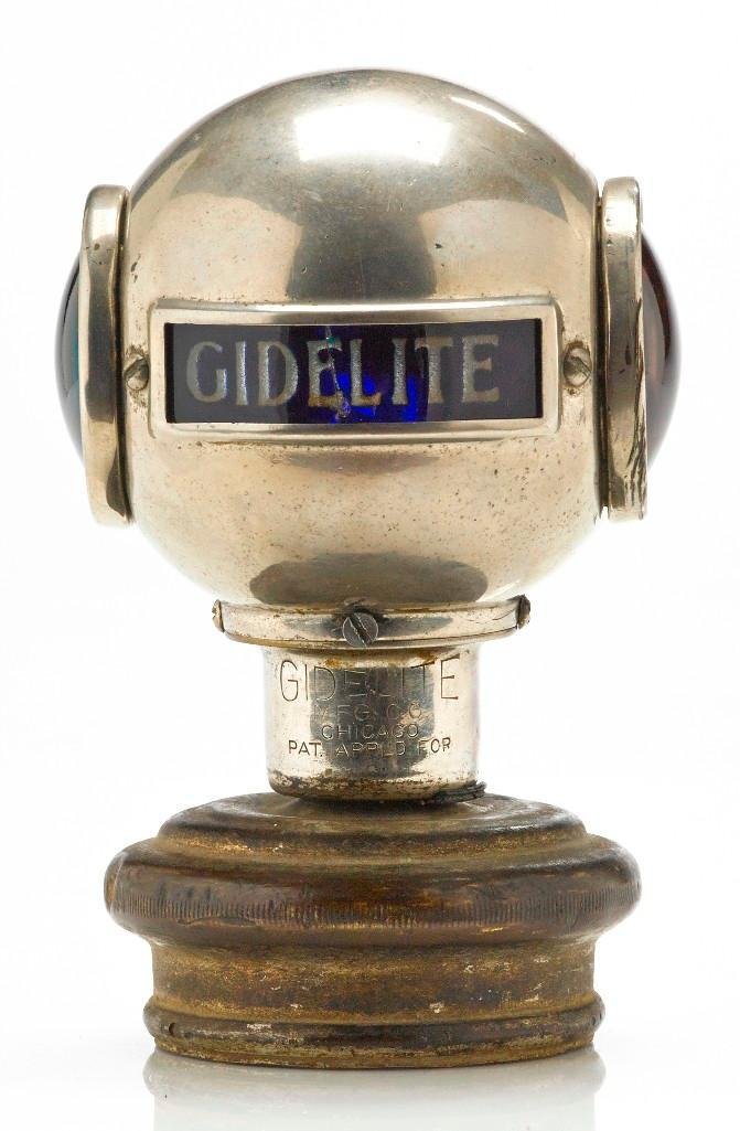GIDELITE MASCOT WITH RED AND GREEN LENSES: Height: 5 inches Sy and Ronnie Margolis's eclectic collection features a wide range of hood or fender ornaments, from about 1909 to recent times. Most date from the 1920s and 1930s, with many from the