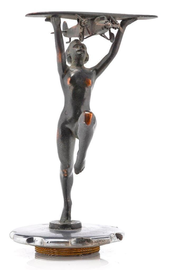 WOMAN HOLDING A FORD TRI-MOTOR PLANE MASCOT: Height: 7 1/4 inches Sy and Ronnie Margolis's eclectic collection features a wide range of hood or fender ornaments, from about 1909 to recent times. Most date from the 1920s and 1930s, with many from