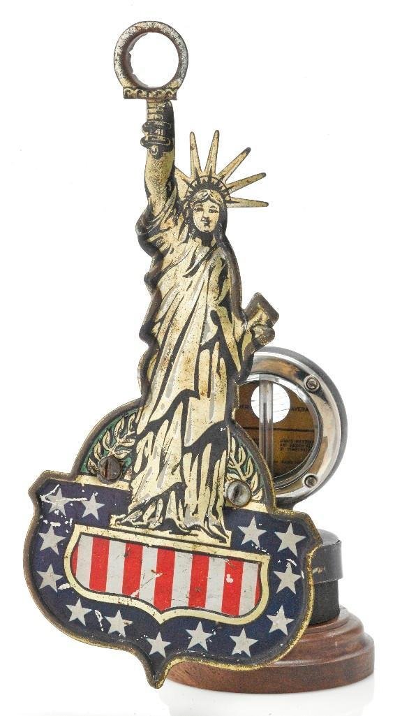 TIN STATUE OF LIBERTY MASCOT WITH MOTO METER: Height: 8 1/2 inches Sy and Ronnie Margolis's eclectic collection features a wide range of hood or fender ornaments, from about 1909 to recent times. Most date from the 1920s and 1930s, with many from