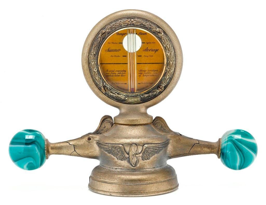 DELUXE MOTO-METER WITH MARBLE DOG BONE CAR MASCOT: Height: 6 inches Length across: 8 1/4 inches Sy and Ronnie Margolis's eclectic collection features a wide range of hood or fender ornaments, from about 1909 to recent times. Most date from the 1920s a