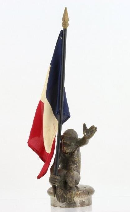 MONKEY HOLDING FRENCH FLAG: Height: 10 inches Sy and Ronnie Margolis's eclectic collection features a wide range of hood or fender ornaments, from about 1909 to recent times. Most date from the 1920s and 1930s, with many from th