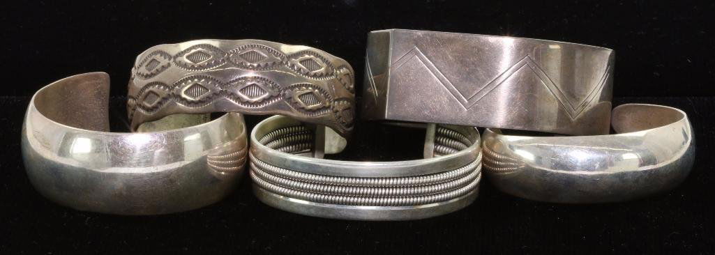 FIVE (5) NATIVE AMERICAN CUFF BRACELETS STERLING SILVER: Various Southwest jewelry makers and designs including one by Sam W. Graves marked sterling the bracelets are varying sizes, largest example approximately 1 inch wide with an inner circumference of ap