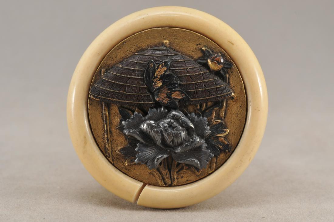 Kagamibuta Netsuke. Japan. ALERT!: Kagamibuta Netsuke. Japan. 19th century. Mixed metal work with high relief decoration of a straw hat and peonies. 1-3/4". Crack to the backing. All items in session one were collected by William H. Sm