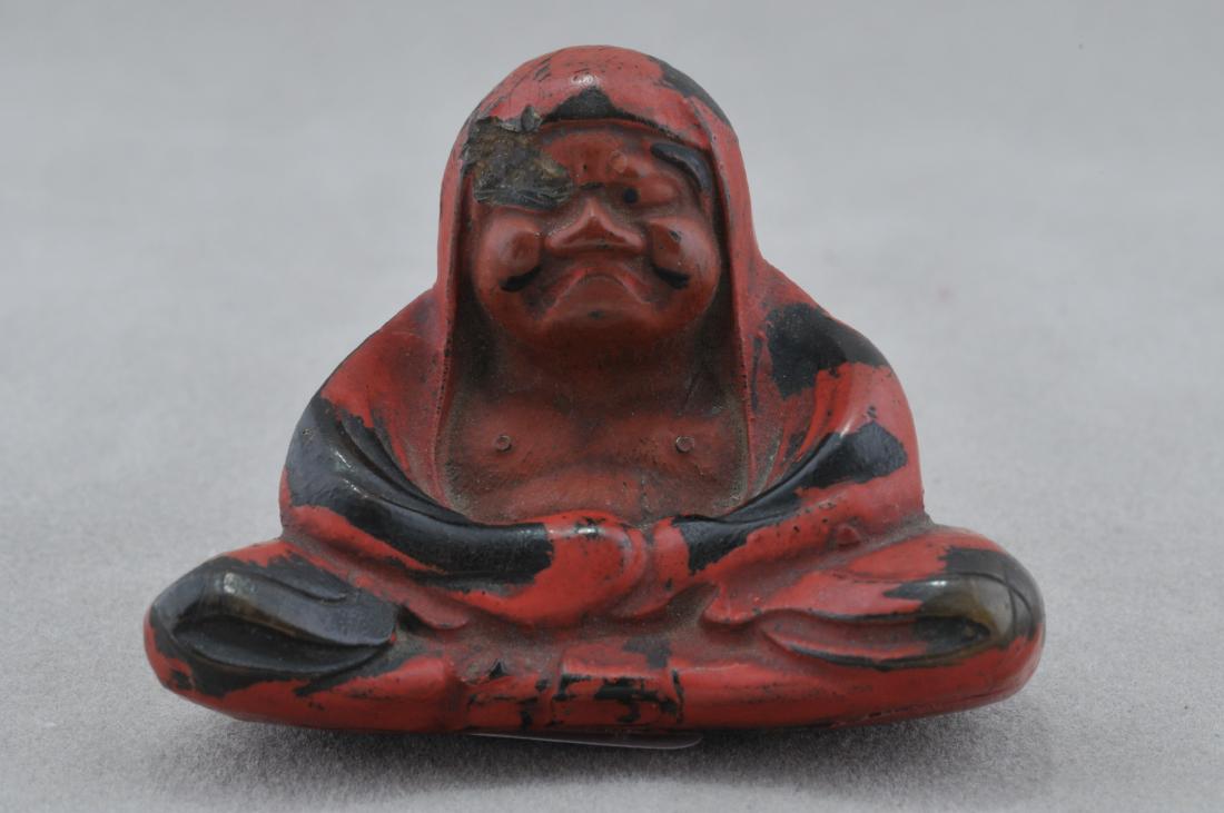 Carved wooden Netsuke. Japan. 19th century. Seated: Carved wooden Netsuke. Japan. 19th century. Seated figure of a Daruma with a negoro lacquered surface. 1-1/2". Chip to the face. All items in session one were collected by William H. Smith (1853-1923)