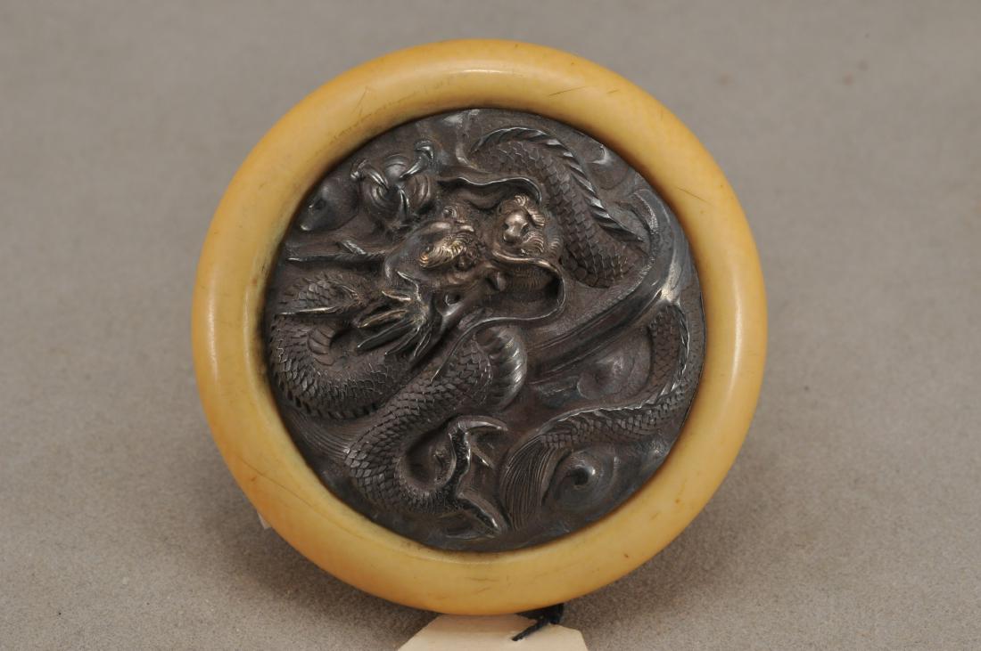Kagamibuta Netsuke. Japan. 19th century. ALERT!: Kagamibuta Netsuke. Japan. 19th century. Repousse silver with a swirling dragon. 1-3/4". All items in session one were collected by William H. Smith (1853-1923)) ALERT!!! ONLY THE CENTRAL INSERTED MED