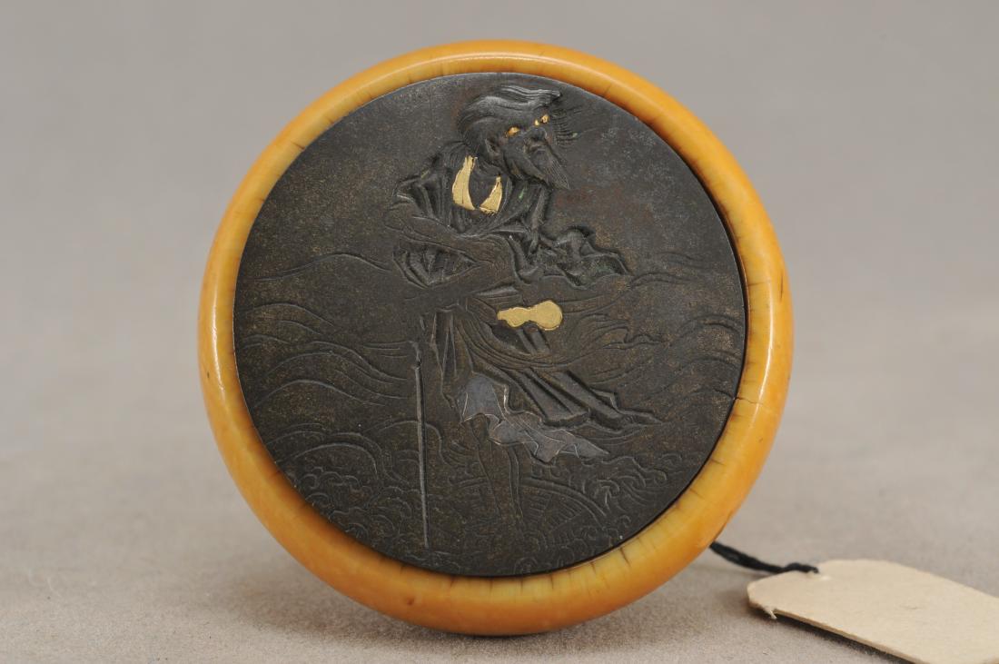 Kagamibuta Netsuke. Japan. 19th century. ALERT!: Kagamibuta Netsuke. Japan. 19th century. Mixed metal work engraved with a sennin crossing the waters on a straw hat. 1-1/2". All items in session one were collected by William H. Smith (1853-1923)) AL