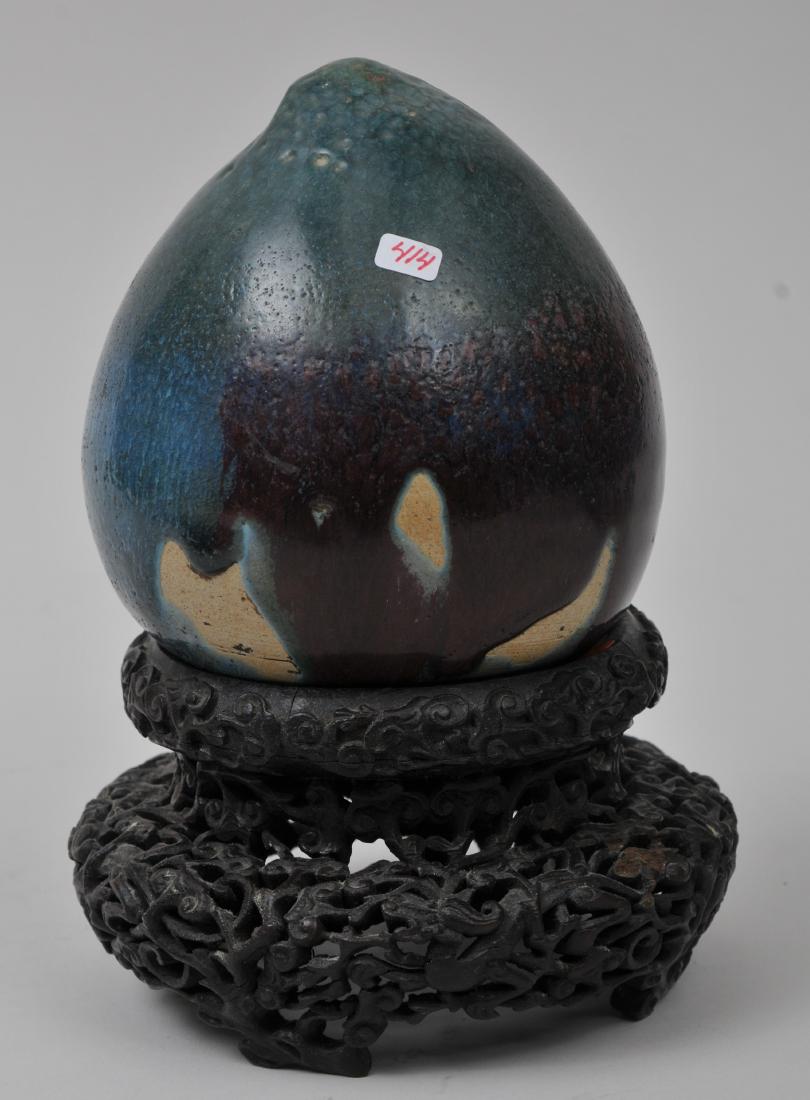 Porcelain peach. China. 19th century. Chien style glaze: Porcelain peach. China. 19th century. Chien style glaze of blue infused with purple. 5-1/2" high. Ornate stand carved with Ling chih and clouds. From the Estate of Jeanette Curuby.