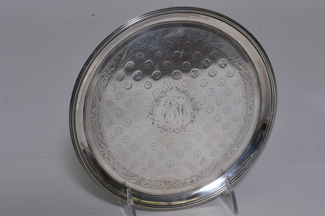 A.E. Warner. Baltimore Coin silver salver with engraved: A.E. Warner. Baltimore Coin silver salver with engraved floral leaf border and interior with round geometric repeating design. Monogrammed. Reeded edge. Marked on base with 11-2 mark. 7-1/2" diameter.