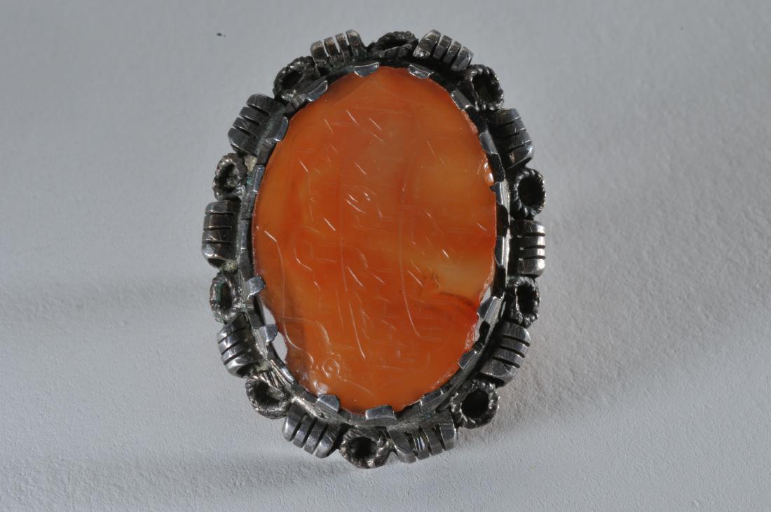 Antique silver and carved agate large ring. Agate stone: Antique silver and carved agate large ring. Agate stone carved with Islamic inscription. Silver unmarked. Chip to agate in corner near edge. Possibly had stones mounted on outer border. 1-3/8" long.