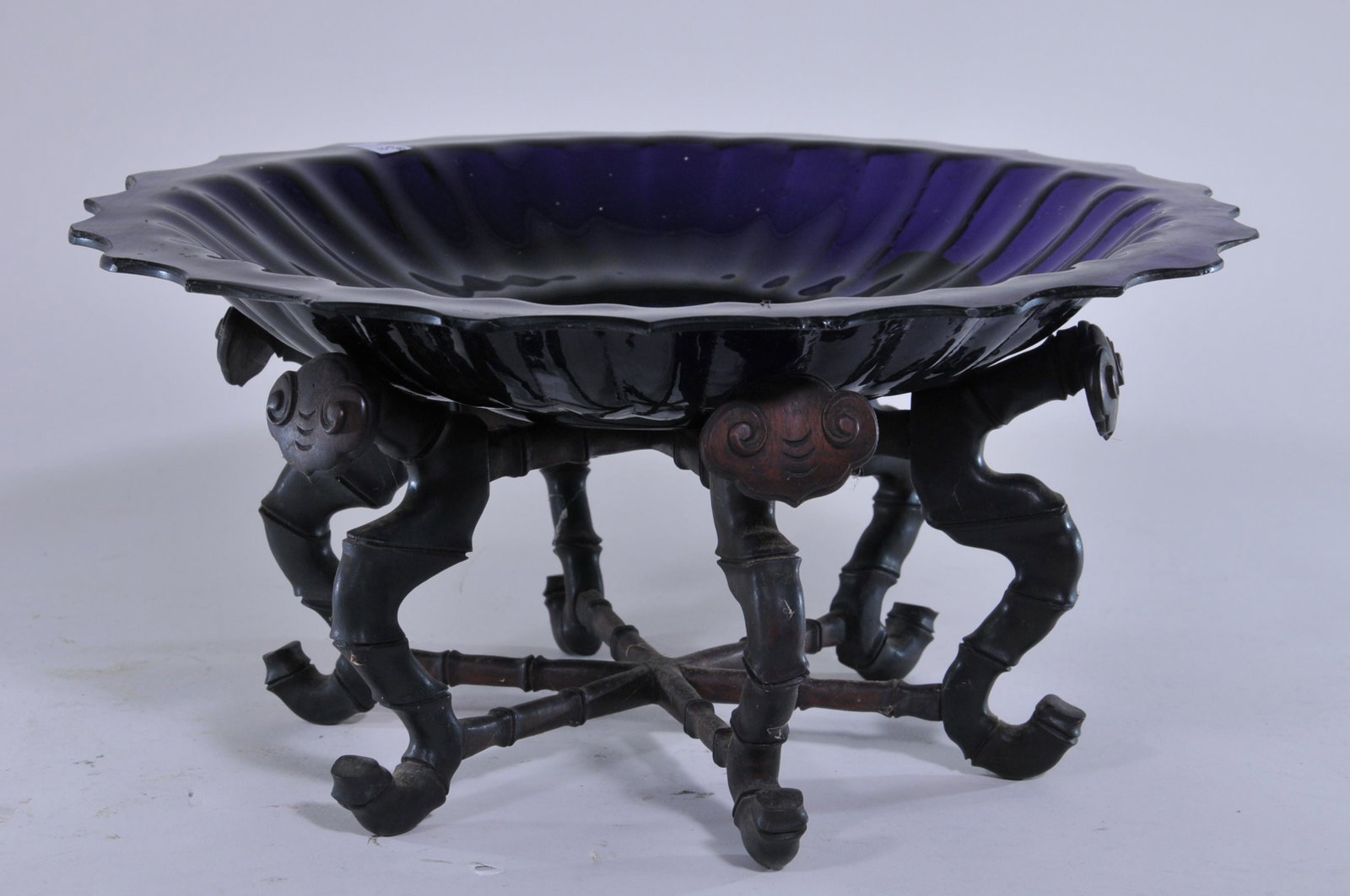 Peking glass bowl. China. Late 19th to early 20th C.: Peking glass bowl. China. Late 19th to early 20th C. Foliate edge, ribbed body. Deep amethyst purple colour. 13". Hardwood stand carved as bamboo and ling Chih. Small edge chips.