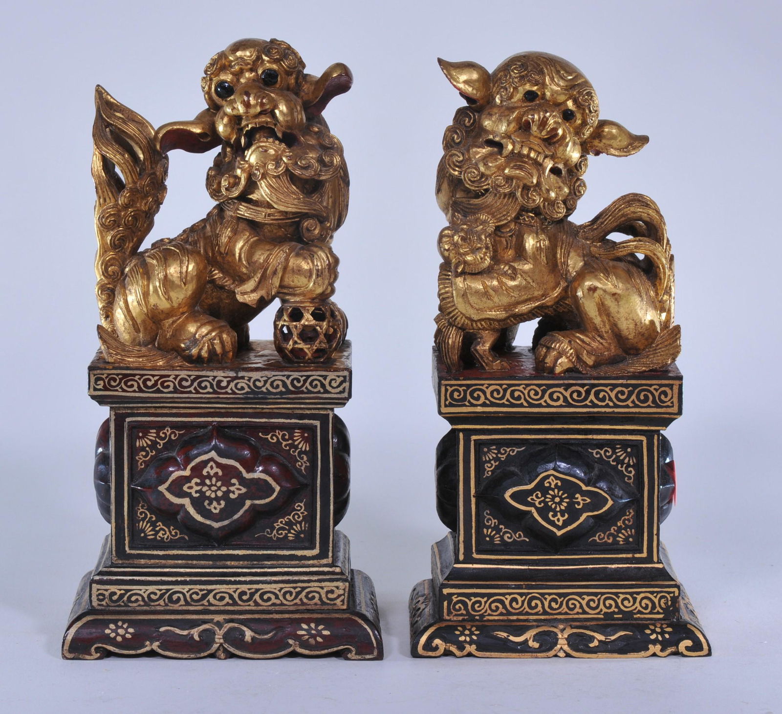 Pair of carved wooden foo dogs. China. Early 20th C.: Pair of carved wooden foo dogs. China. Early 20th C. Surface lacquered in red and black with gilding. 9-3/4"H.