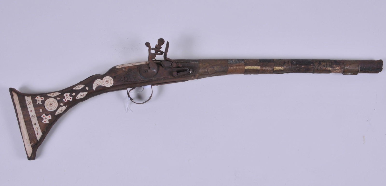 Antique Middle Eastern Flint Lock Saddle gun 27": Antique Middle Eastern Flint Lock Saddle gun 27" overall, with what appears to be bone inlay and five brass barrel bands. Frizzen is stuck closed.