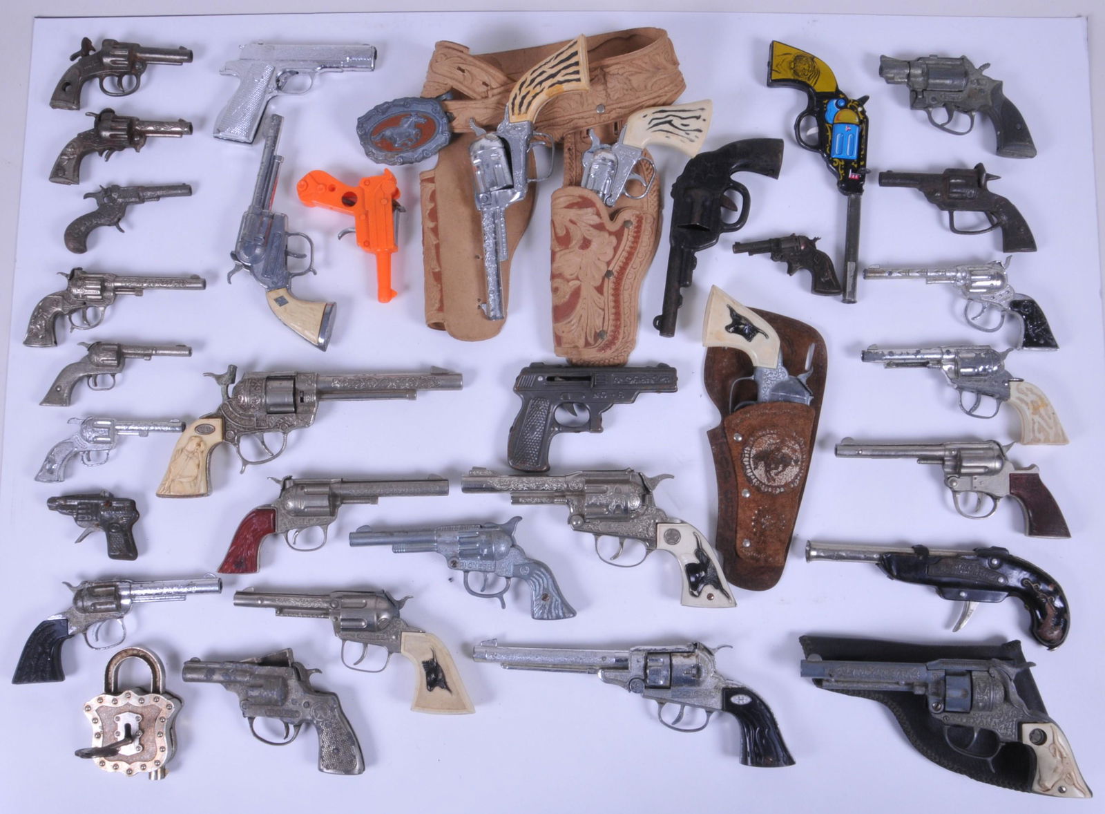 Box lot of toy cap guns with 33 toy guns and one: Box lot of toy cap guns with 33 toy guns and one holster belt and a single holster. Also one toy chest lock with key.