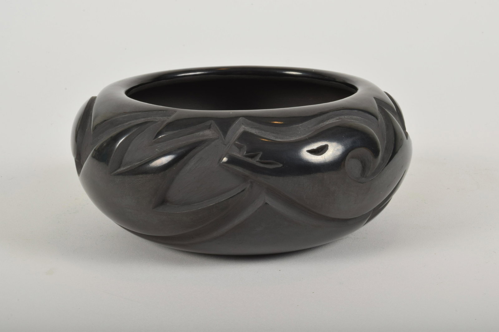 Joseph Naranjo Santa Clara Pueblo Blackware Pottery: Joseph Naranjo Santa Clara Pueblo Blackware Pottery Bowl. Deep carved flowing animalistic design of a wolf to the sides, signed to underside. 7Â” x 3 ¼Â”.