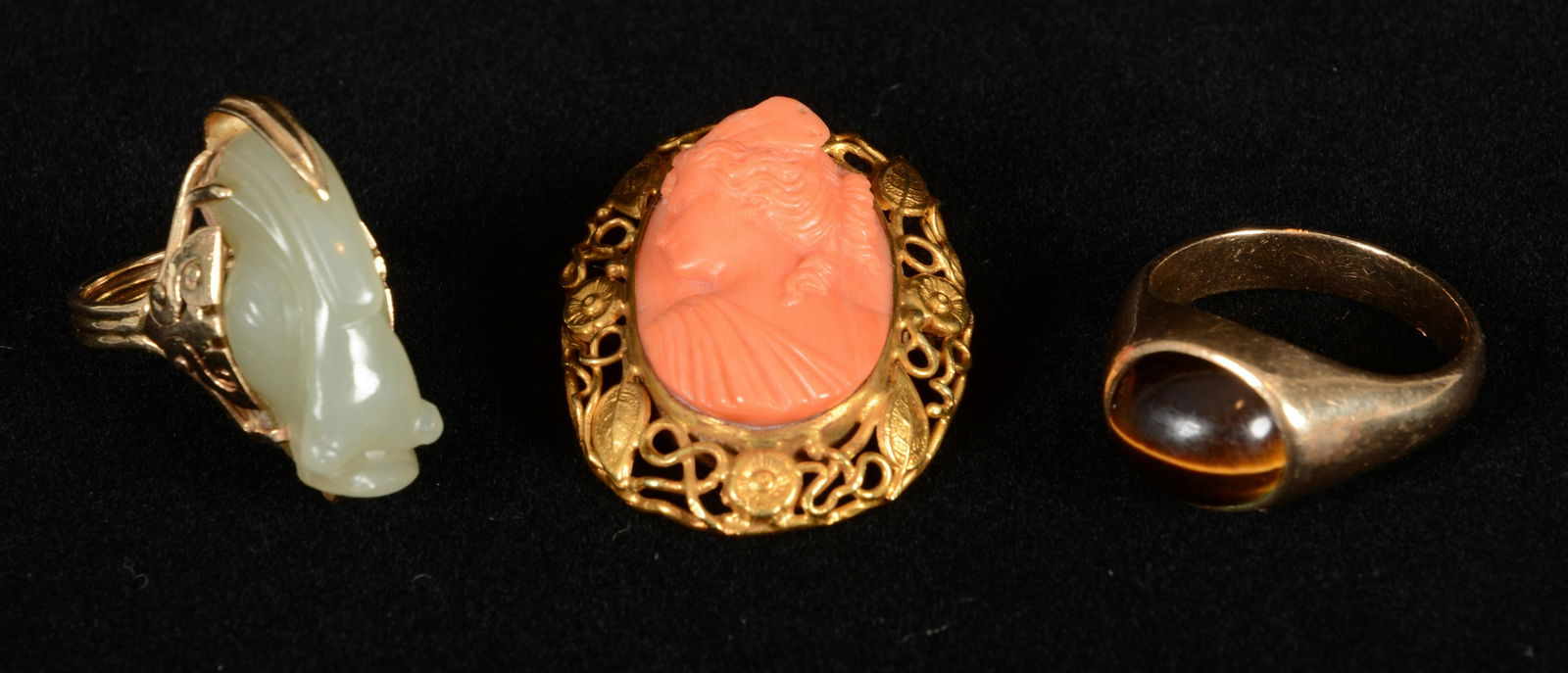 Three Pieces Gold Jewelry: Lot of three pieces of gold jewelry. To include: (1) 14 karat gold ring with carved white jade figural toad or frog. Mount marked 14 kt. 1” long. (2) 10 karat gold ring mounted with a tiger eye