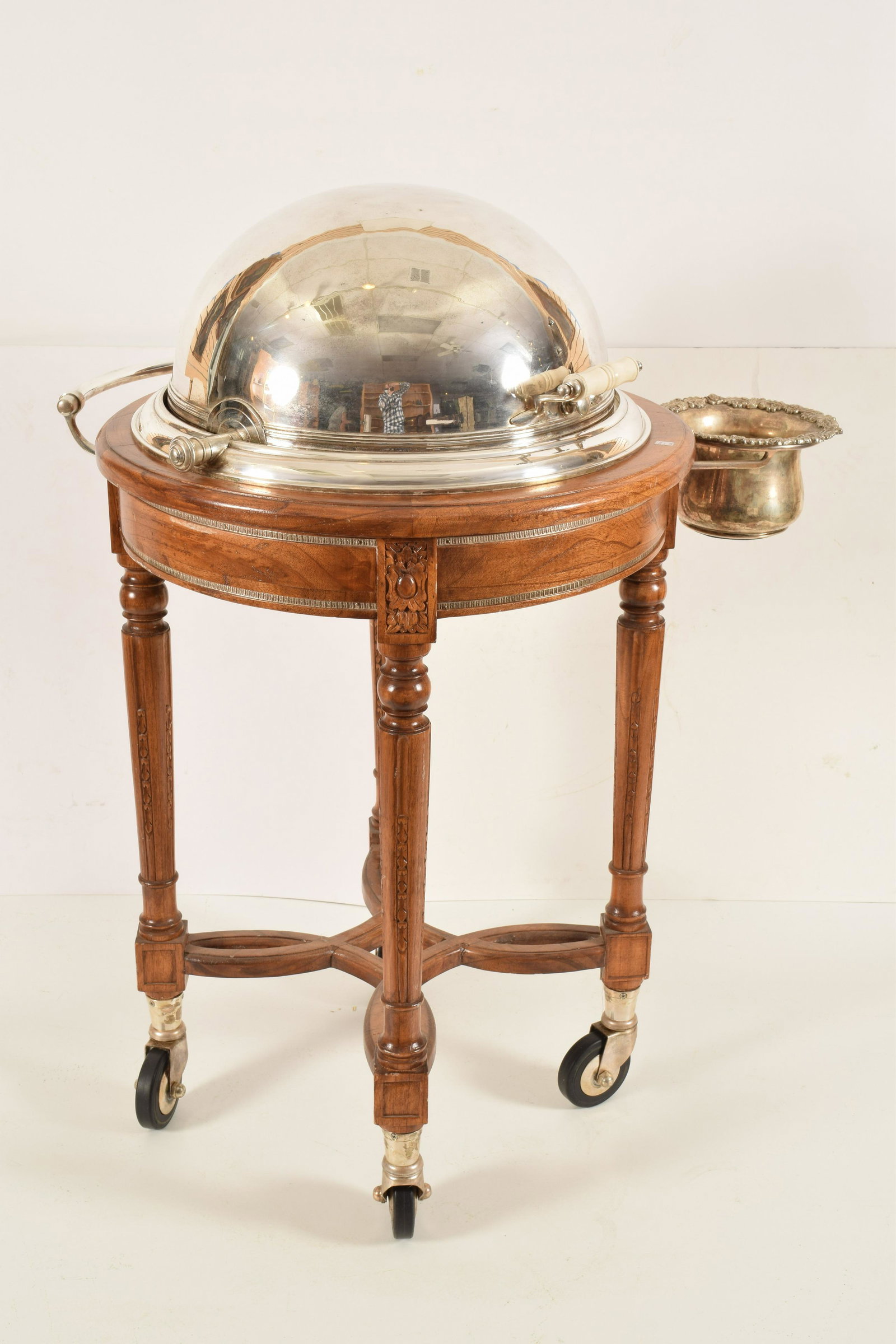 20th Century Sheffield Silver Plate Wine Trolley: 20th century Sheffield silver plate roll away wine trolley. Carved walnut French style. Four leg stand with interlaced cross stretcher locking revolving hide away silver-plated dome top revealing seve