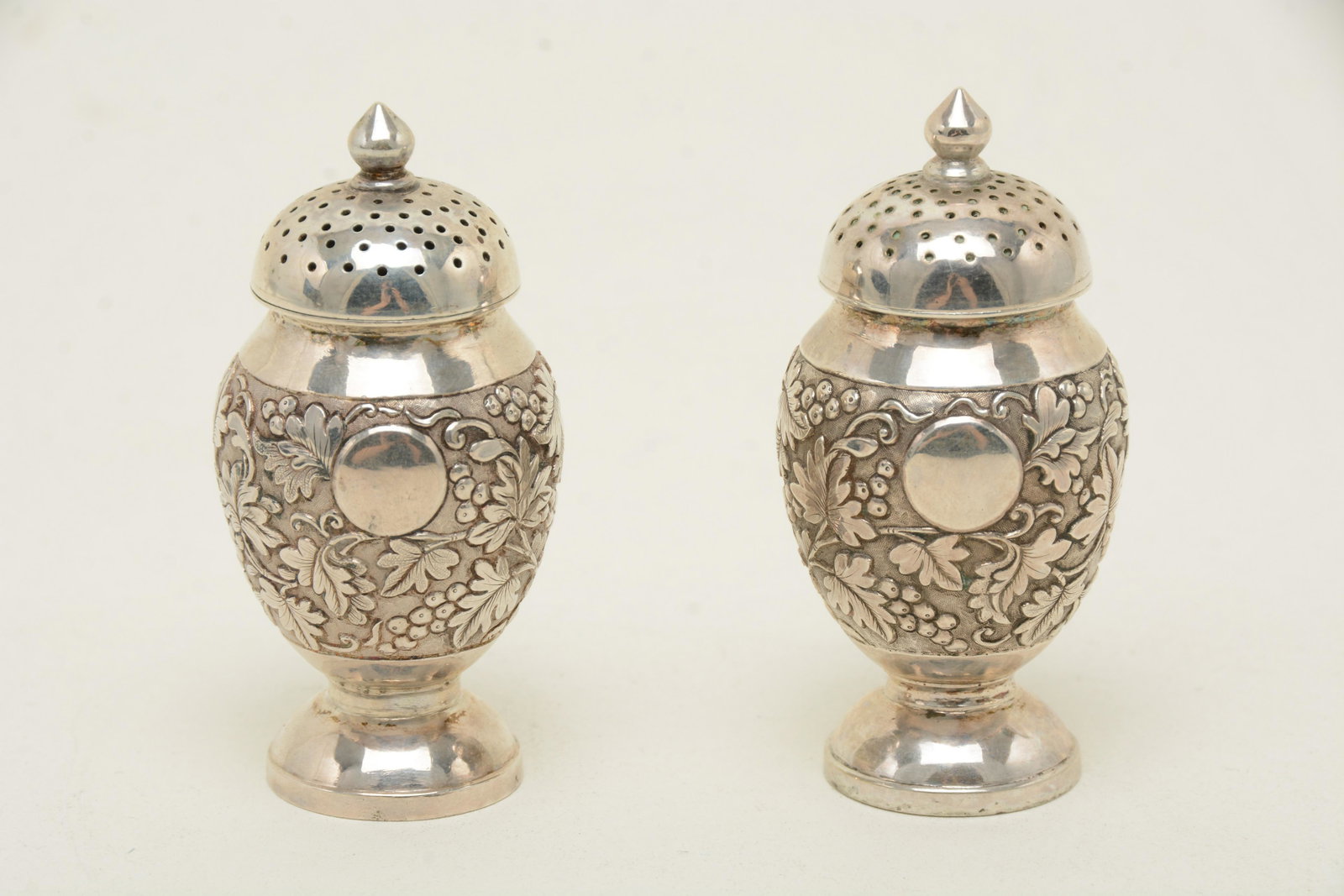 Chinese export silver pepper shakers, pair, marked: Chinese export silver pepper shakers, pair, marked Gothic K. Marked with Gothic K and an ideogram. Maker unidentified but Canton, mid-19th century. Foliate chasing on the body, applied ring base, thre