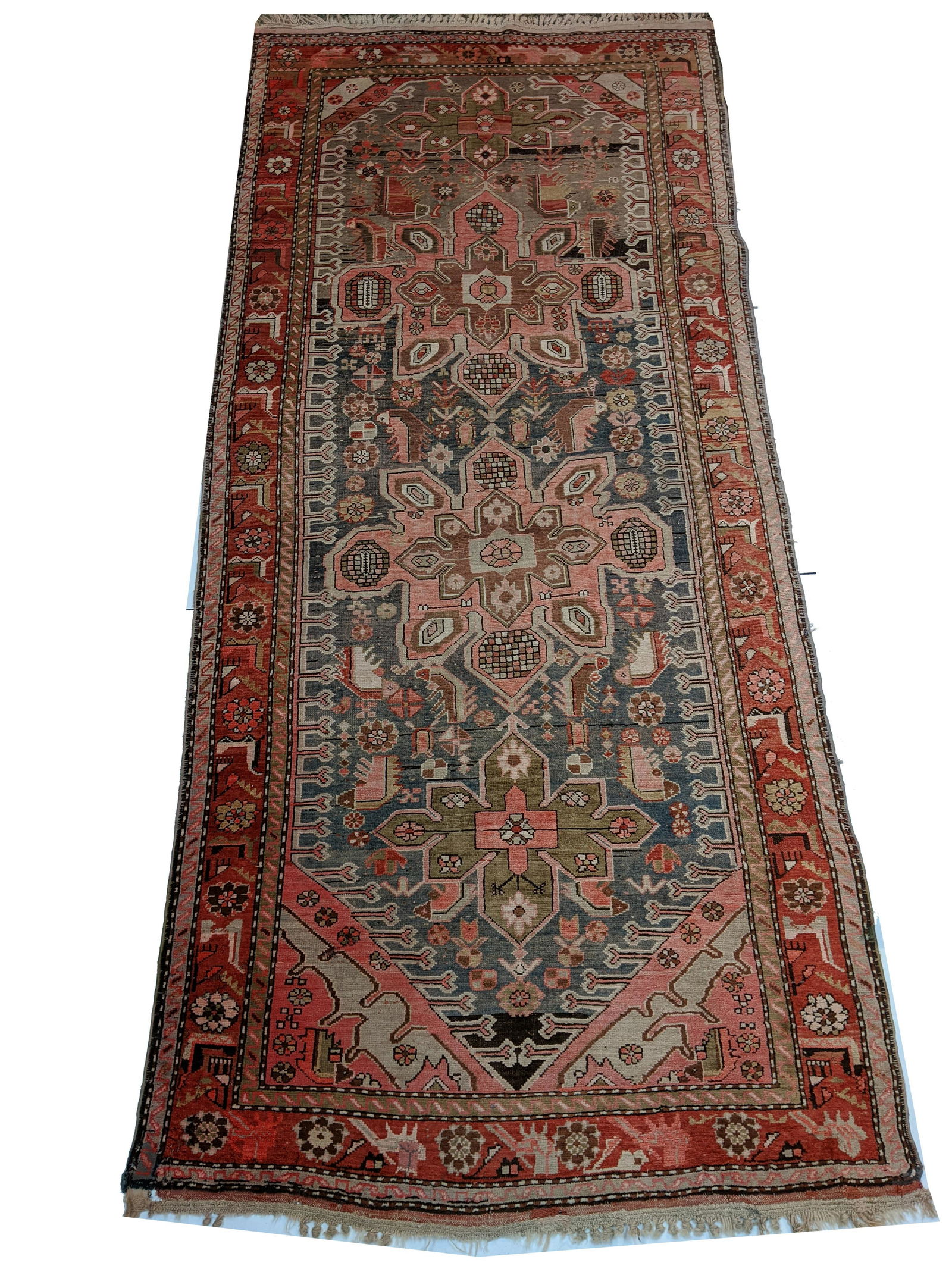 Hand-Knotted Wool Long Rug. 4 star medallion center: Hand-Knotted Wool Long Rug. 4 star medallion center with light blue/grey tone main field with figural and geometric guls surrounded by red and gold borders. 112” x 49.5”. Fading overall, s