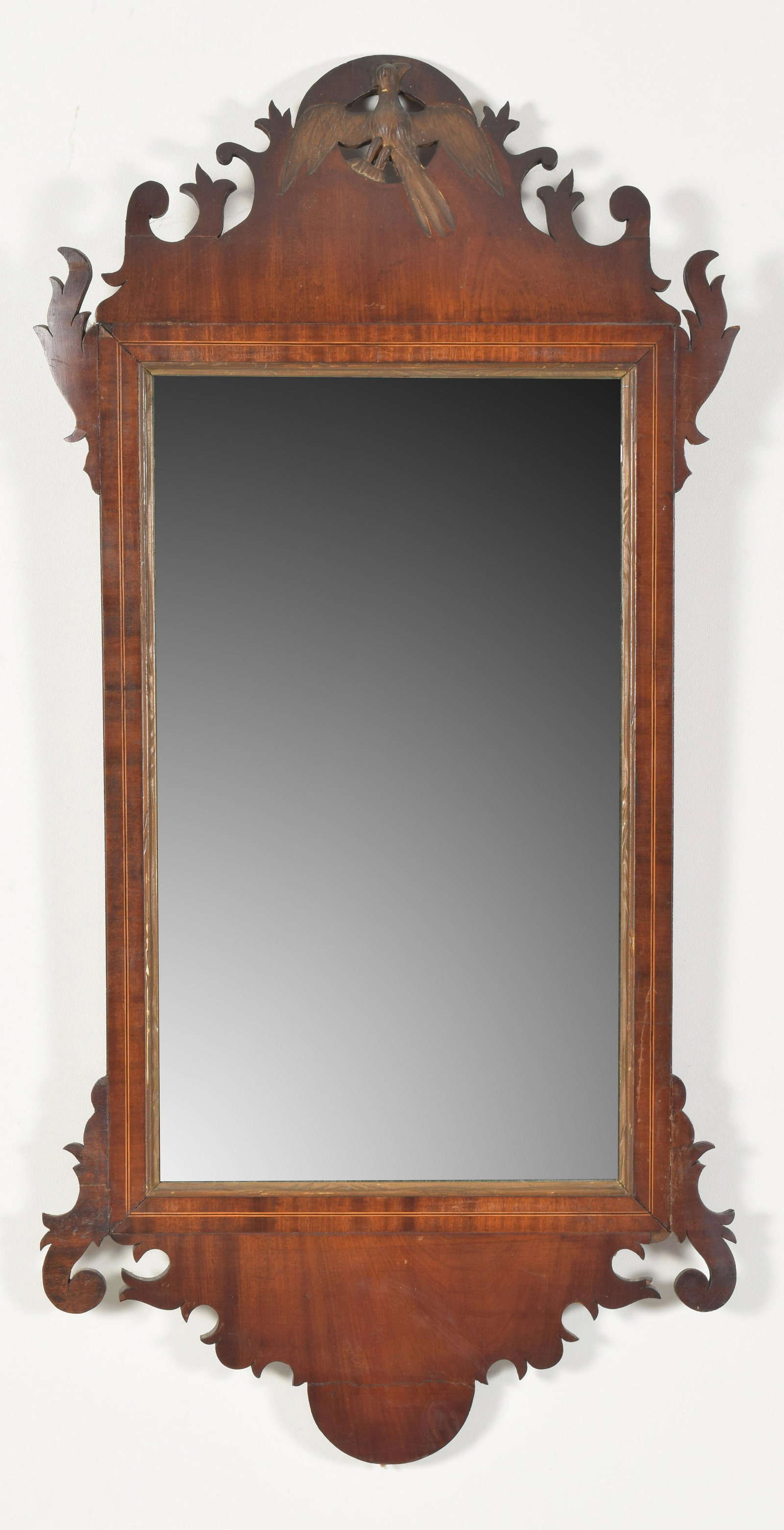 Chippendale mahogany mirror with shaped crest carved: Chippendale mahogany mirror with shaped crest carved with a gilt phoenix bird, circa 1780. Gilt molded frame with line inlay around a period mirror glass. 42 x 20.25” Repairs to ears and crest. 
