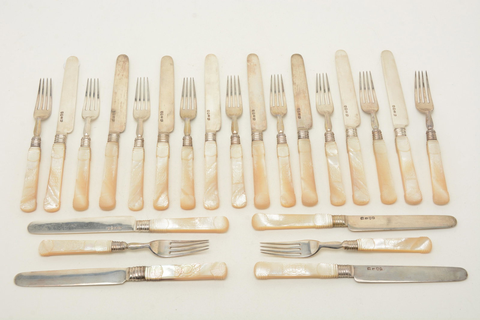 Wong Shing Chinese export silver forks and knives,: Wong Shing Chinese export silver forks and knives, Canton, mid-19th C. Carved mother-of pearl handles, with 2 shells and flower. Length of knives 8-3/8", forks 6-7/8". No monogram. 12 knives and 11 fo
