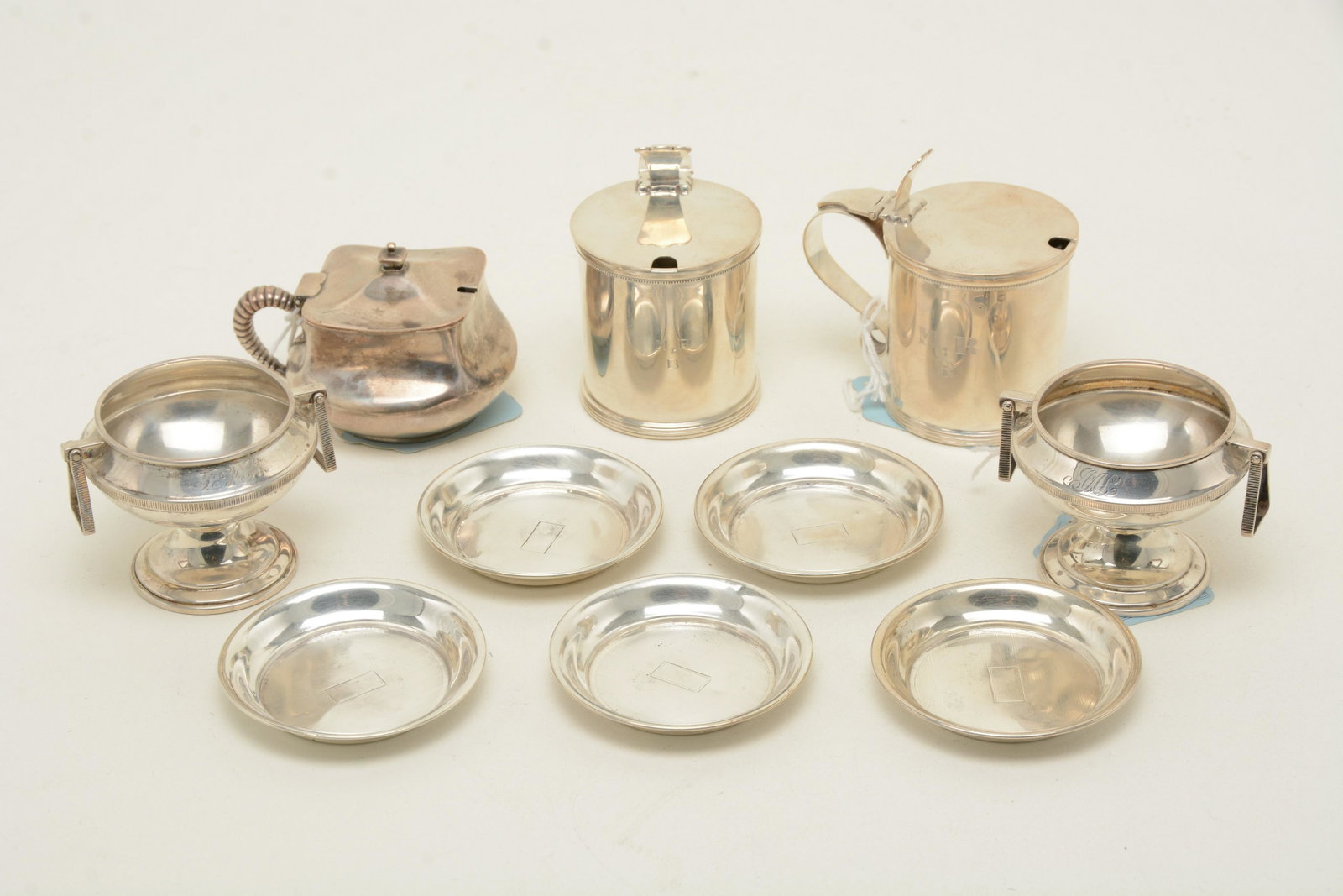 Sterling silver mustard pots and salt cellars. Includes: Sterling silver mustard pots and salt cellars. Includes a pair of pots by Stieff, ca. 1950s, with colorless glass inserts (monogram MRB), a single mustard pot by Dominick & Haff, a pair of footed salt