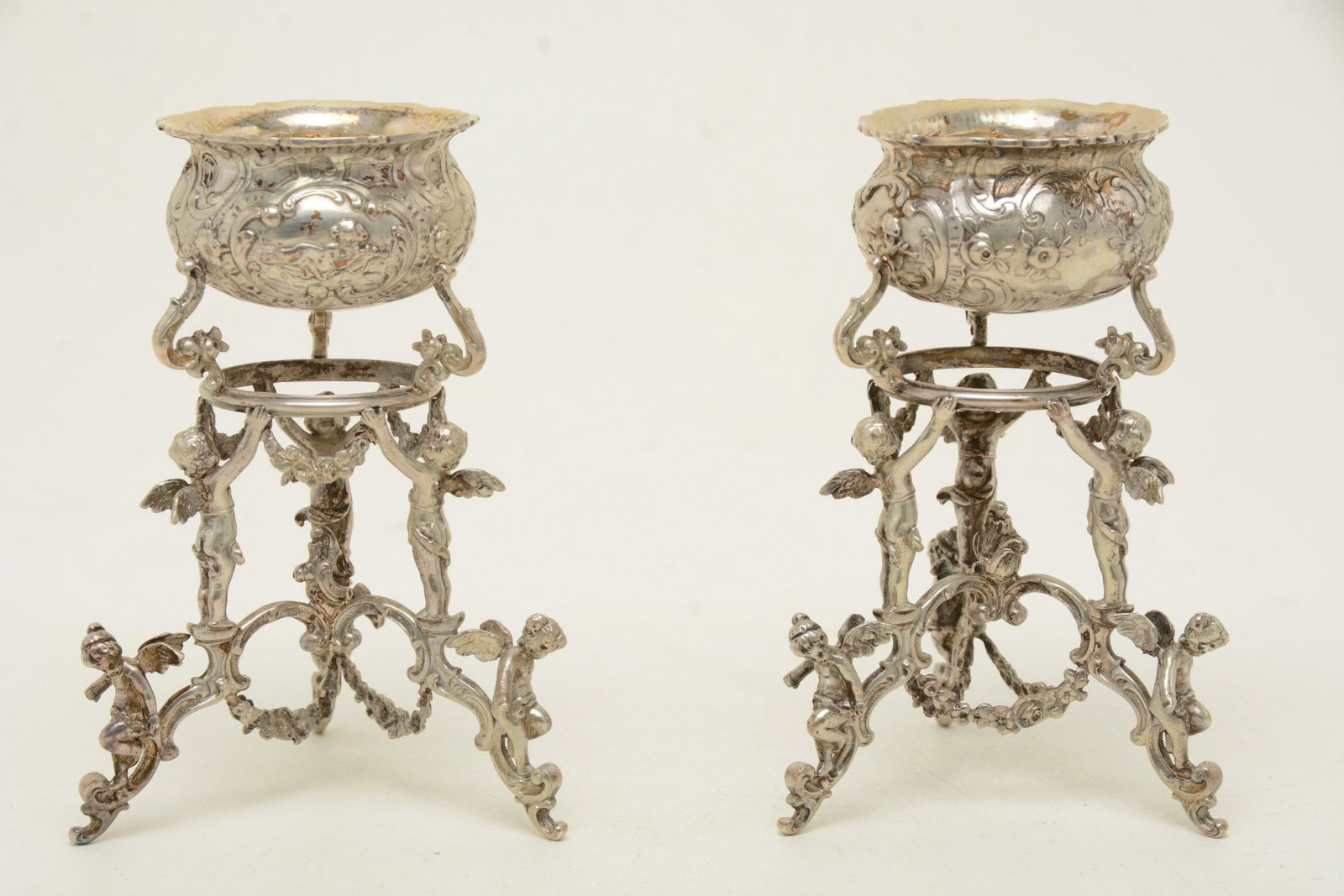 Pair 19th/20th century .800 silver continental tall: Pair 19th/20th century .800 silver continental tall footed master salts. Figural cherub supports. Cherub and floral decorated bowls. Marked on side of bowls. Good condition. 4.75” high. 11.3 ozt
