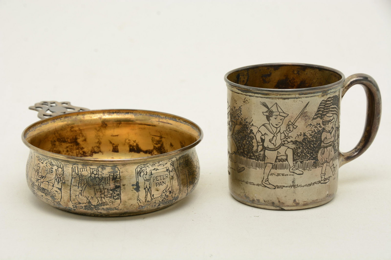 Webster sterling silver two-piece child’s set.: Webster sterling silver two-piece child’s set. Porringer with acid etched decorated panels with titles. PanPan scenes and titles. Wear to some titles and small dent on body near base. Cup with a