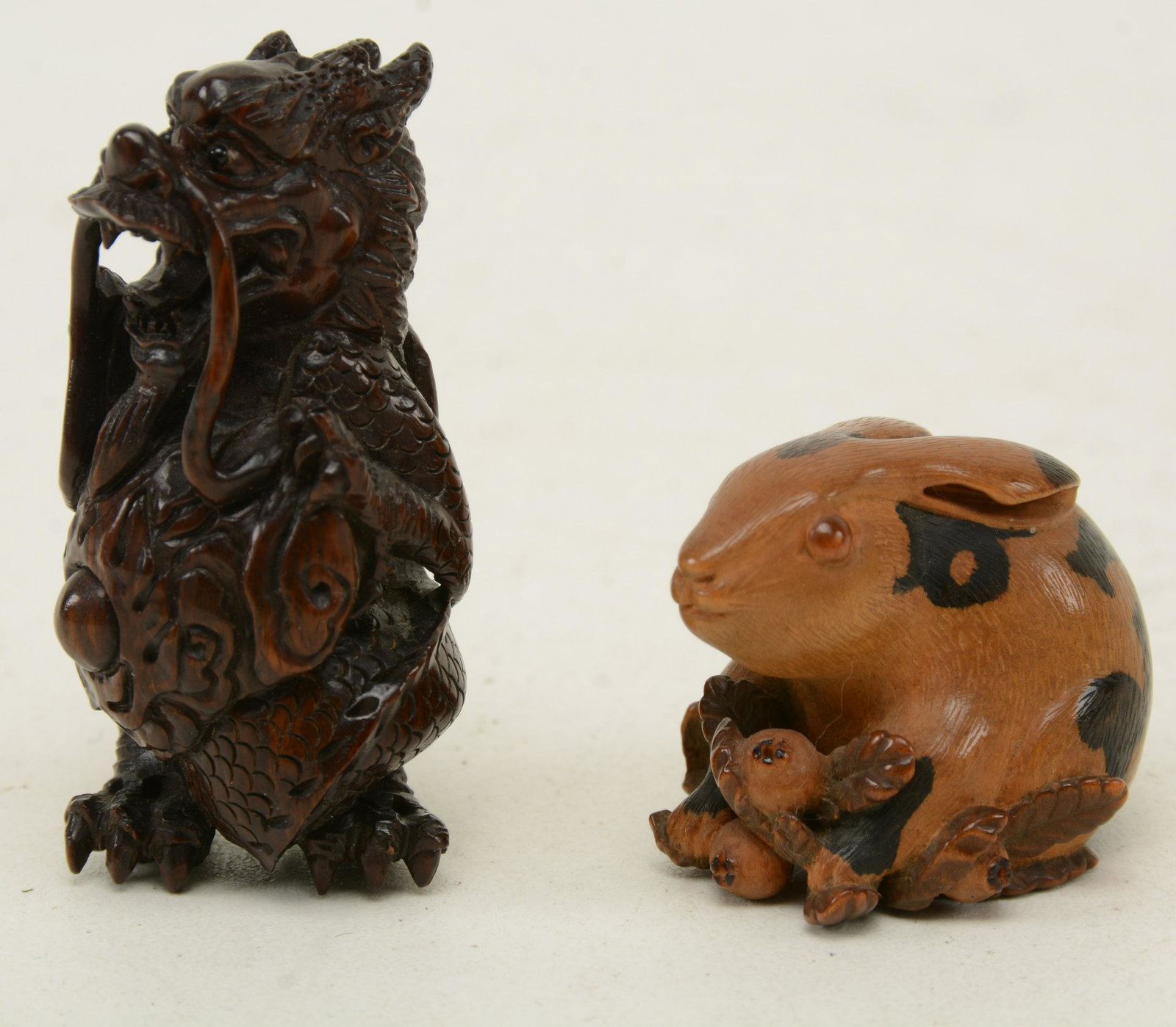 two carved wood Japanese Netsukes. A standing dragon.: two carved wood Japanese Netsukes. A standing dragon. Height 2.25; other Carved and stained wood sitting hare holding fruit. Height 1 3/16 in
