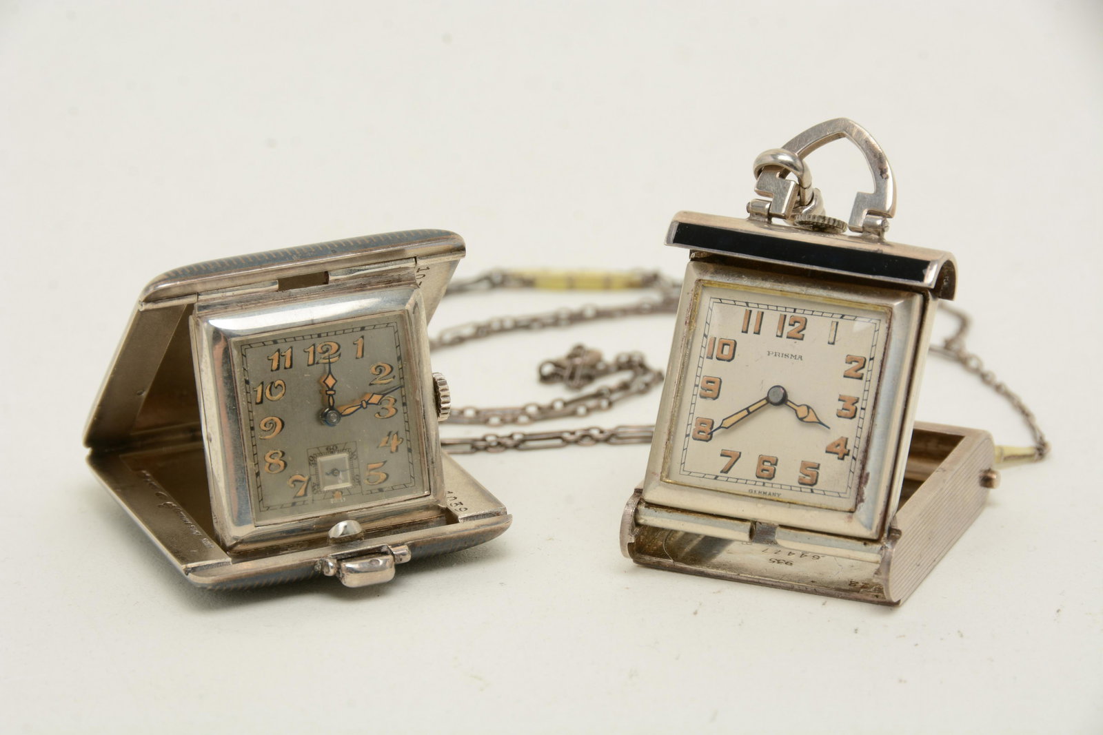 2 miniature silver travel clocks, "Prisma" sterling: 2 miniature silver travel clocks, "Prisma" sterling silver and back enameled case, marked 935 64477 patent no. 1651804 sterling German, with chain, case 2in x 1 1/8in, chain length 17in, sterling silv