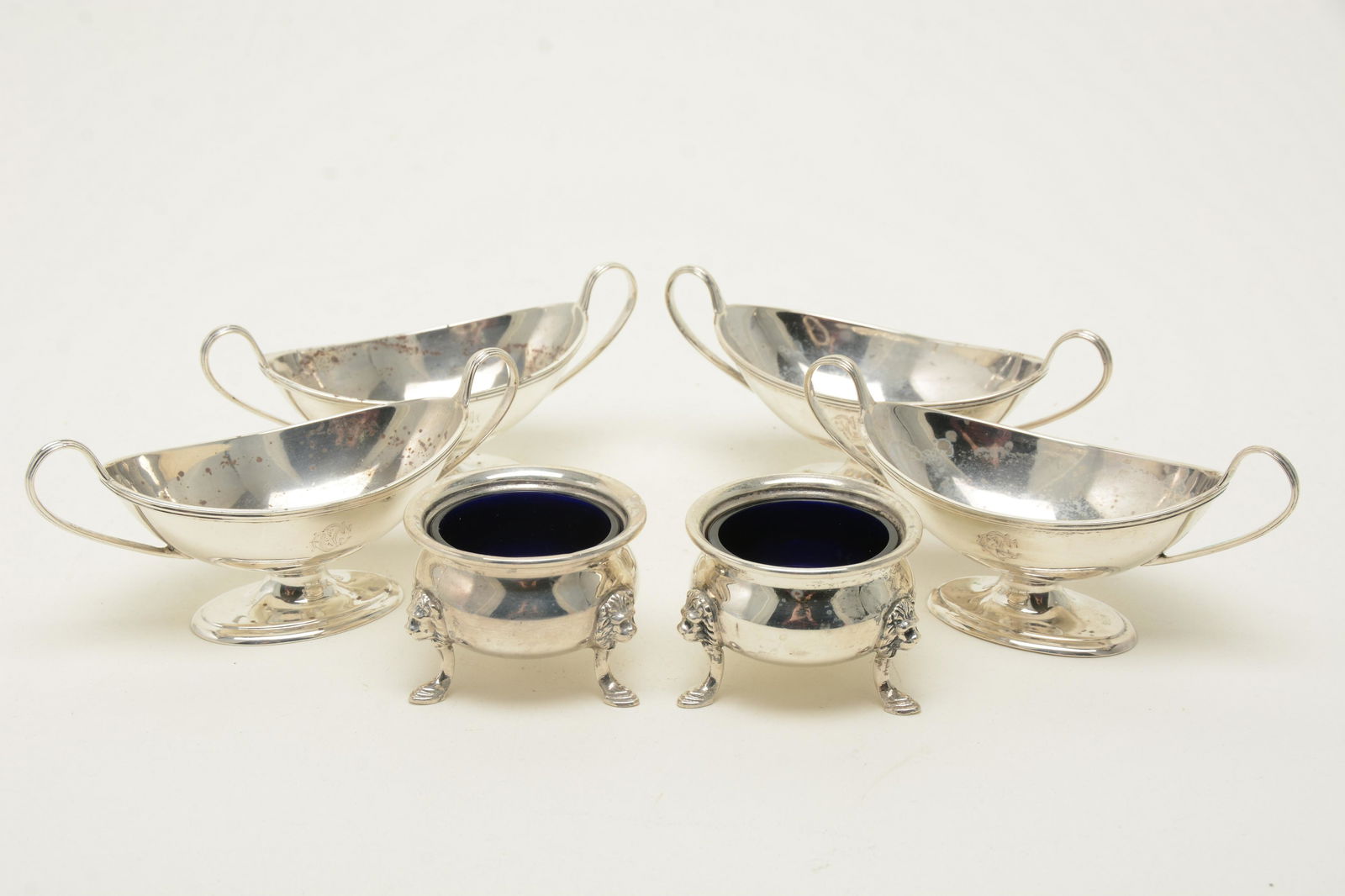 Sterling silver salt cellars. Set of [4] Victorian: Sterling silver salt cellars. Set of [4] Victorian sterling silver two-handle footed salt dishes. Hallmarks for London, 1884. Makerâ€™s mark of TB JH in a shield cartouche. Together with pair of
