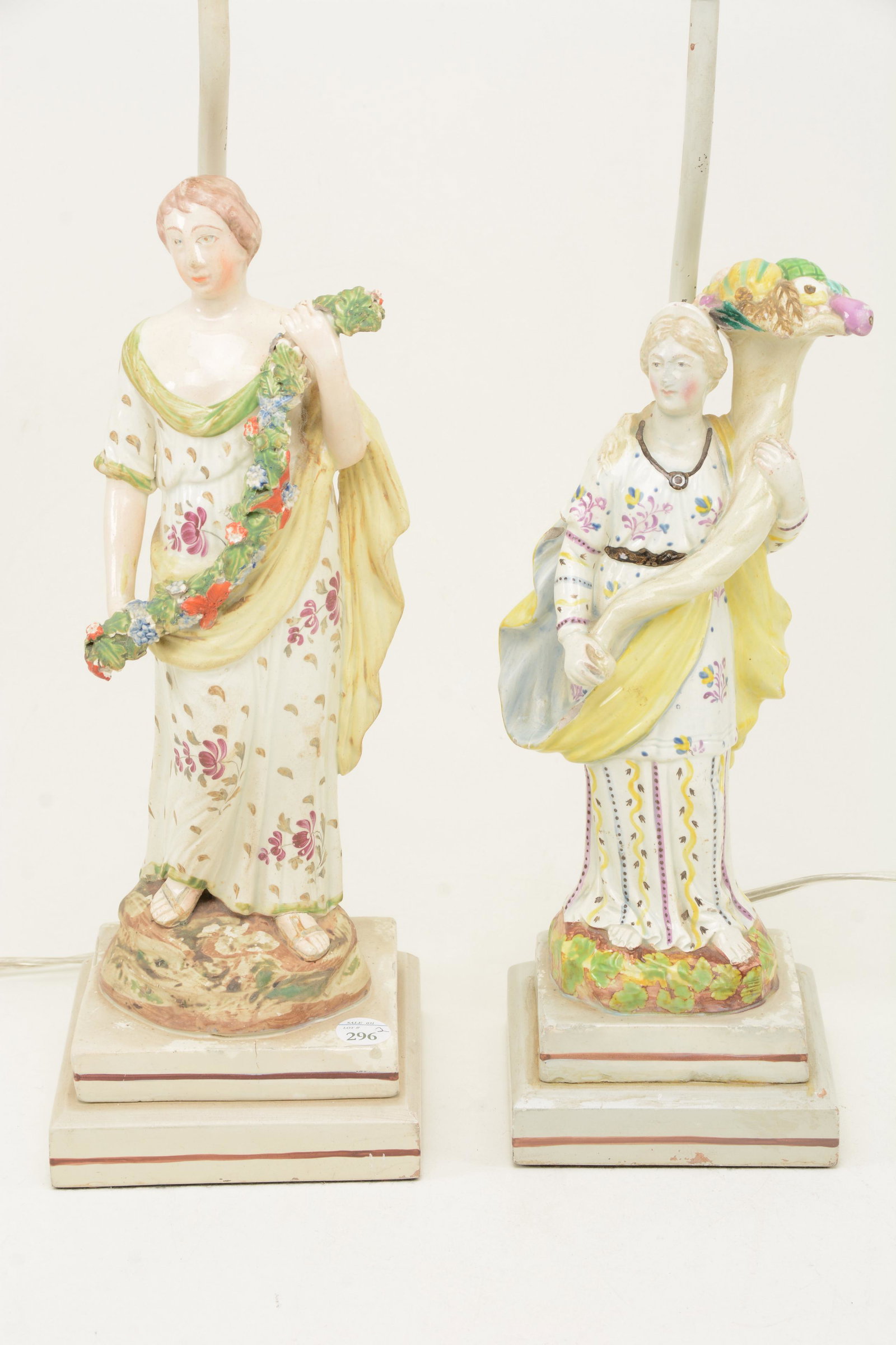 19th century English creamware ceramic figures.: 19th century English creamware ceramic figures. Neoclassical female figures in floral decorated robes with cornucopia and garland. Mounted as lamps. Various small surface chips and losses. Smallest fi