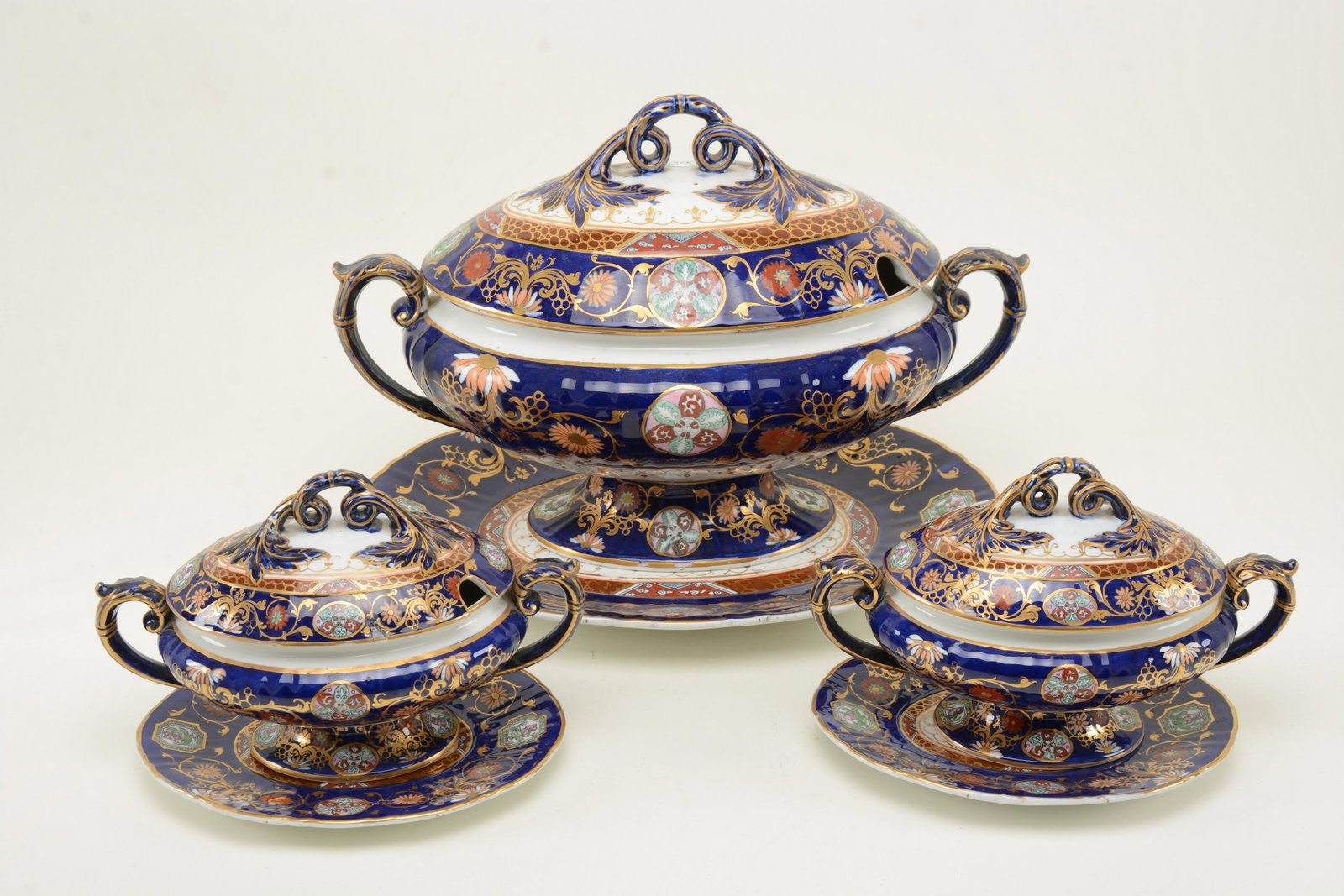 English Ironstone Covered Tureens and Trays. One large: English Ironstone Covered Tureens and Trays. One large tureen with pair of smaller tureens. All with undertrays. Ornately hand-decorated and highly gilt on blue grounds with floral motifs and pinwheel