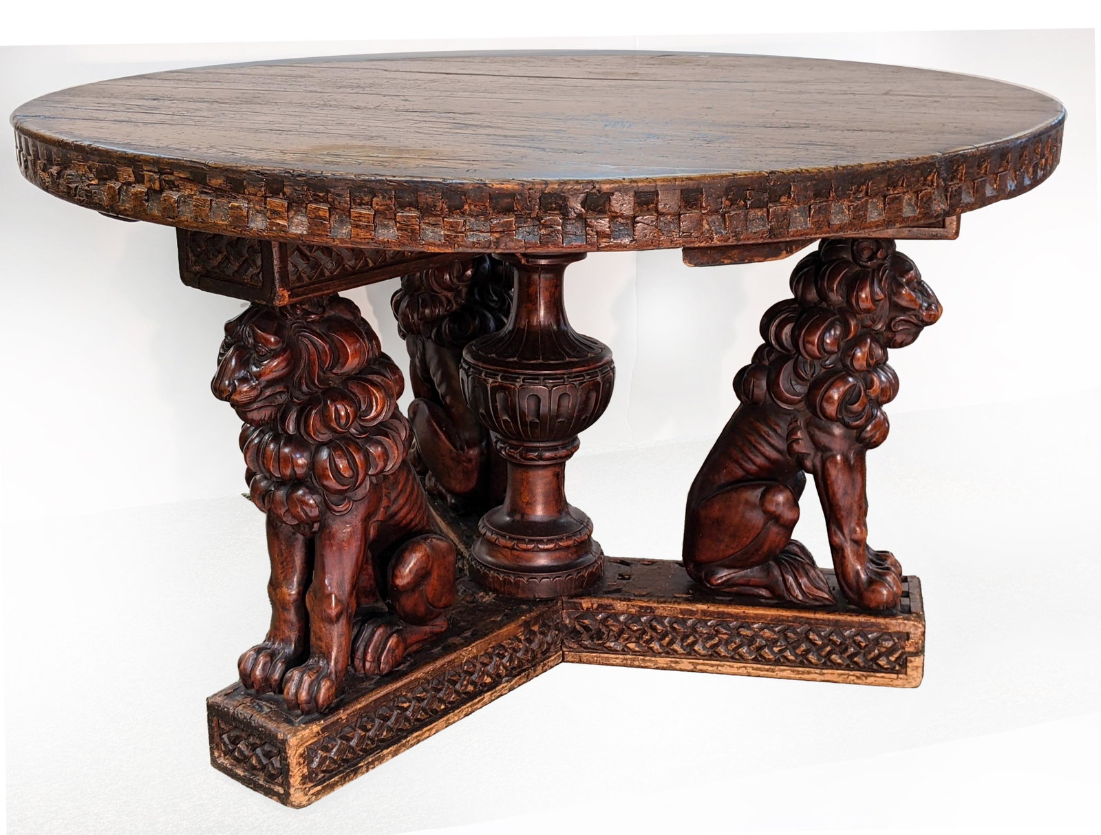 Antique Continental round oak and mahogany dining table: Antique Continental round oak and mahogany dining table with lion form base. Round top with a checkerboard edge on a large vasiform post with three carved seated lion supports. Made from early element