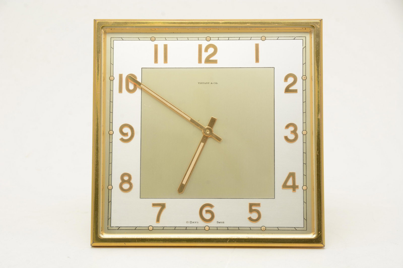 Tiffany & Co. Brass and beveled glass desk clock.: Tiffany & Co. Brass and beveled glass desk clock. Eight.day swiss movement. Wear to finishon brass edges and stand. Monogrammed on top. 5.75in square