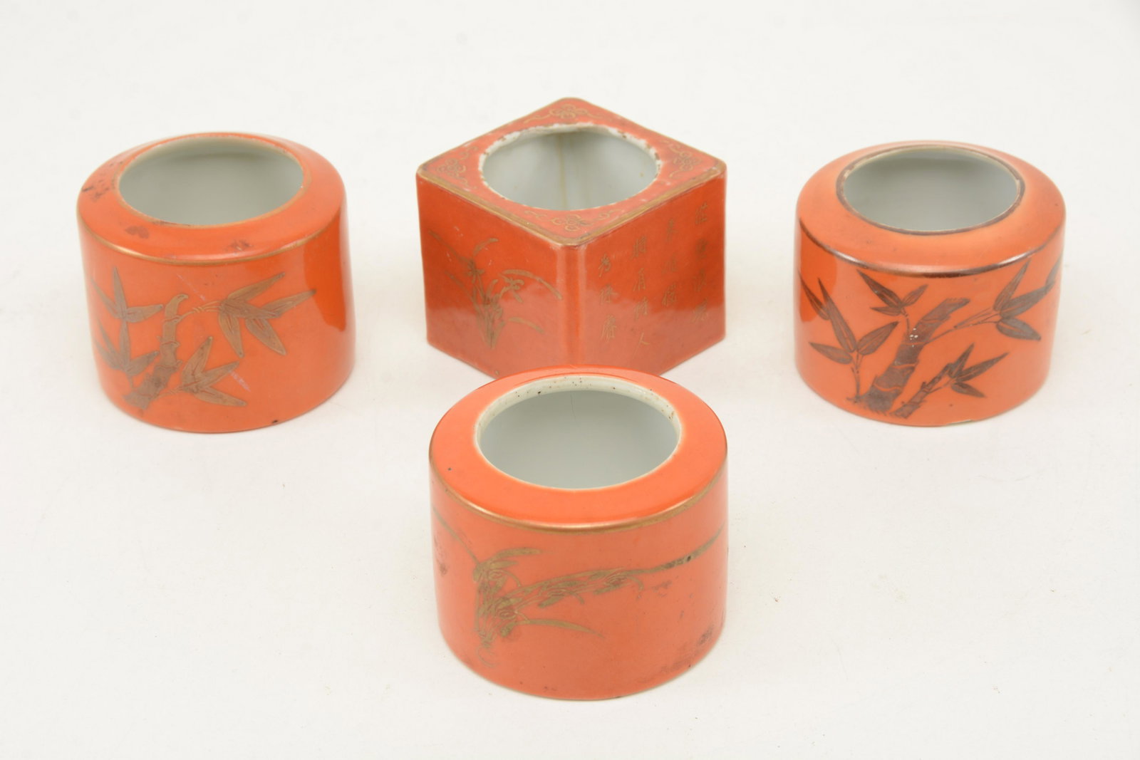 4 orange ground porcelain brush washers. Gilt foliate: 4 orange ground porcelain brush washers. Gilt foliate decoration with inscriptions. One with crack/break and repair. Others exhibiting small chips. 2.75 height of round washer.