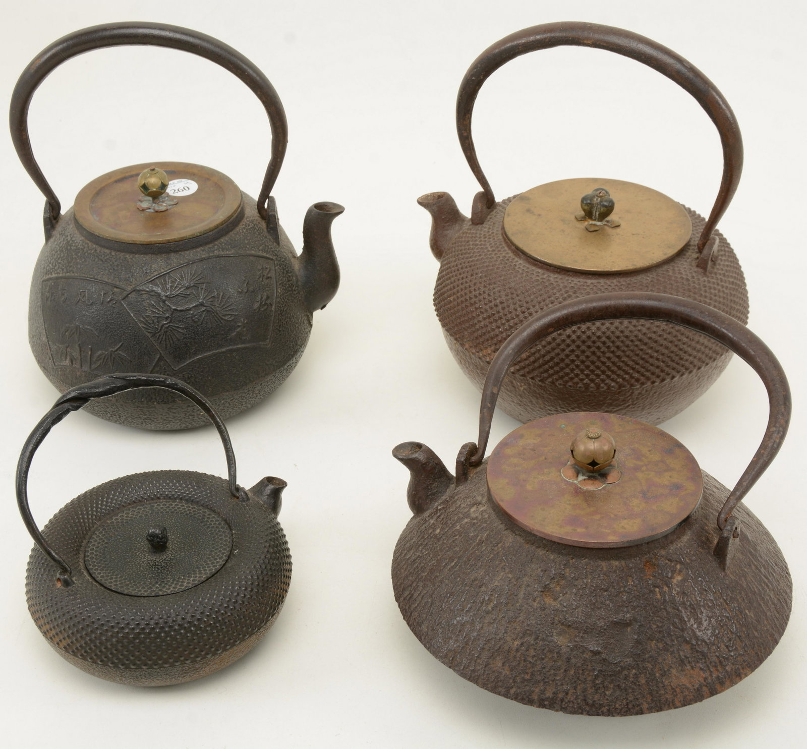 4 Japanese cast iron teapots. One with bamboo scenes: 4 Japanese cast iron teapots. One with bamboo scenes and inscription. Others display various textured surfaces. 8.75 in height of tallest with handle up.
