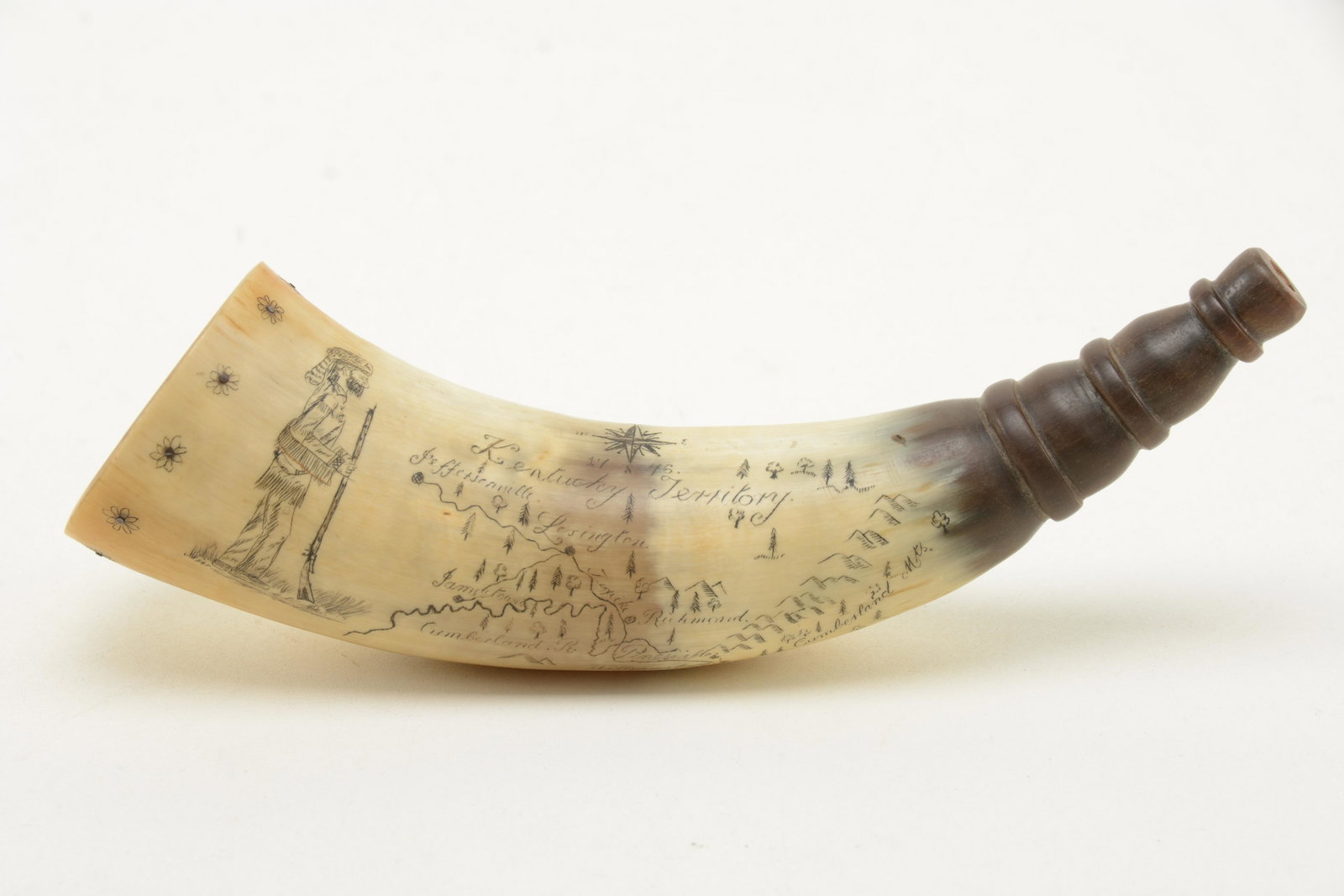 Kentucky Territory scrimshaw powder horn. Depictions of: Kentucky Territory scrimshaw powder horn. Depictions of a frontier man with rifle. Map showing Williamsburg, Richmond, and Jeffersonville. Wood cap. 20th century. Length 8in.