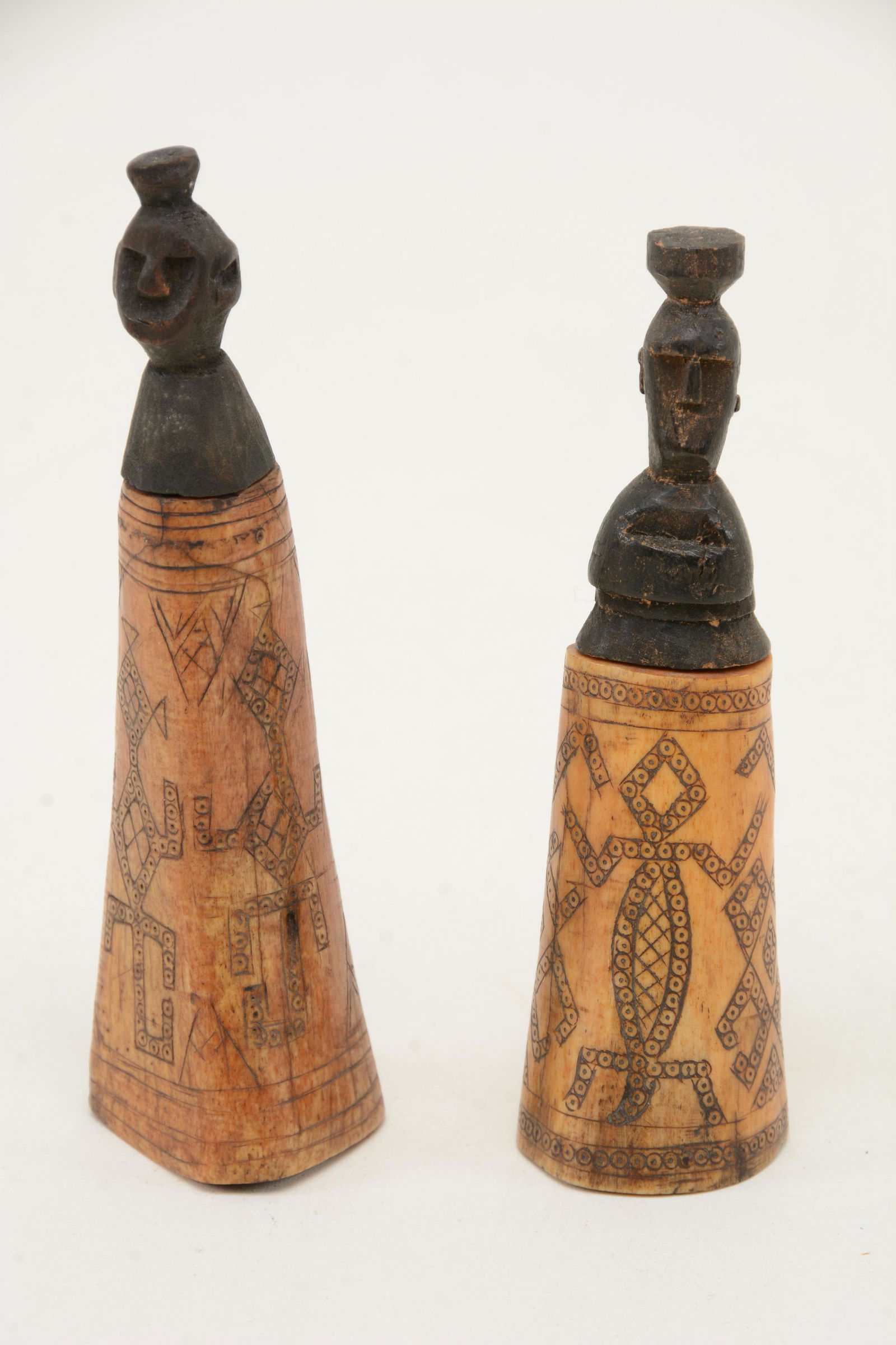 2 horns with incised geometric decoration. Wood tops: 2 horns with incised geometric decoration. Wood tops carved with human figures. Height 5 in and 5.5 in.