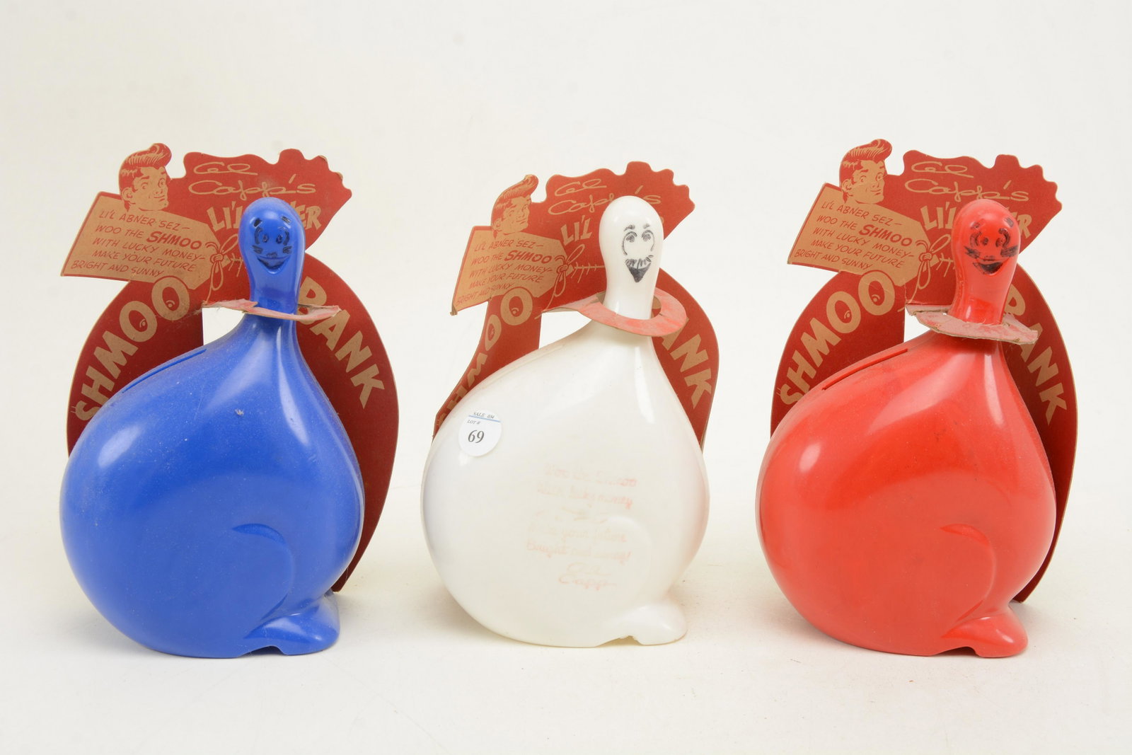 Lil Abner Shmoo banks in red, white, and blue. Complete: Lil Abner Shmoo banks in red, white, and blue. Complete with original paper labels. Height of each 8 in.