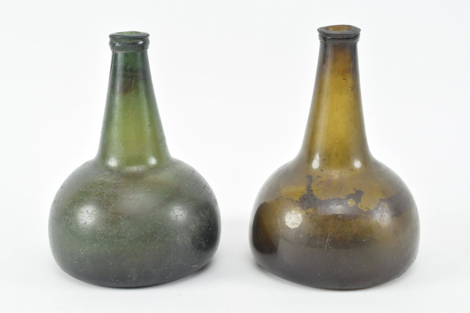 2 18th century Dutch glass onion form wine bottles.: 2 18th century Dutch glass onion form wine bottles. Green and amber/green colored glass. Amber tone bottle with breaks and repairs. Pontil marks present. Each 7.75in high.