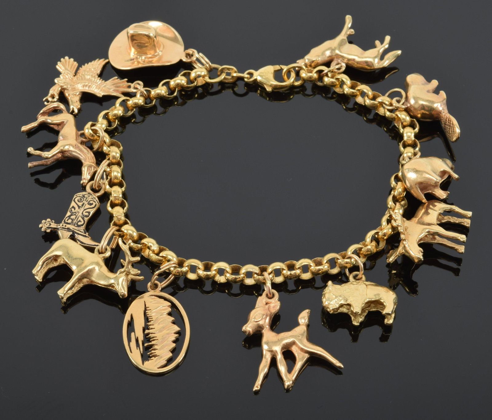 14K yellow gold charm bracelet, simple links with with: 14K yellow gold charm bracelet, simple links with with 12 charms, mostly Western themes. Length, 8” 25.7 dwt.