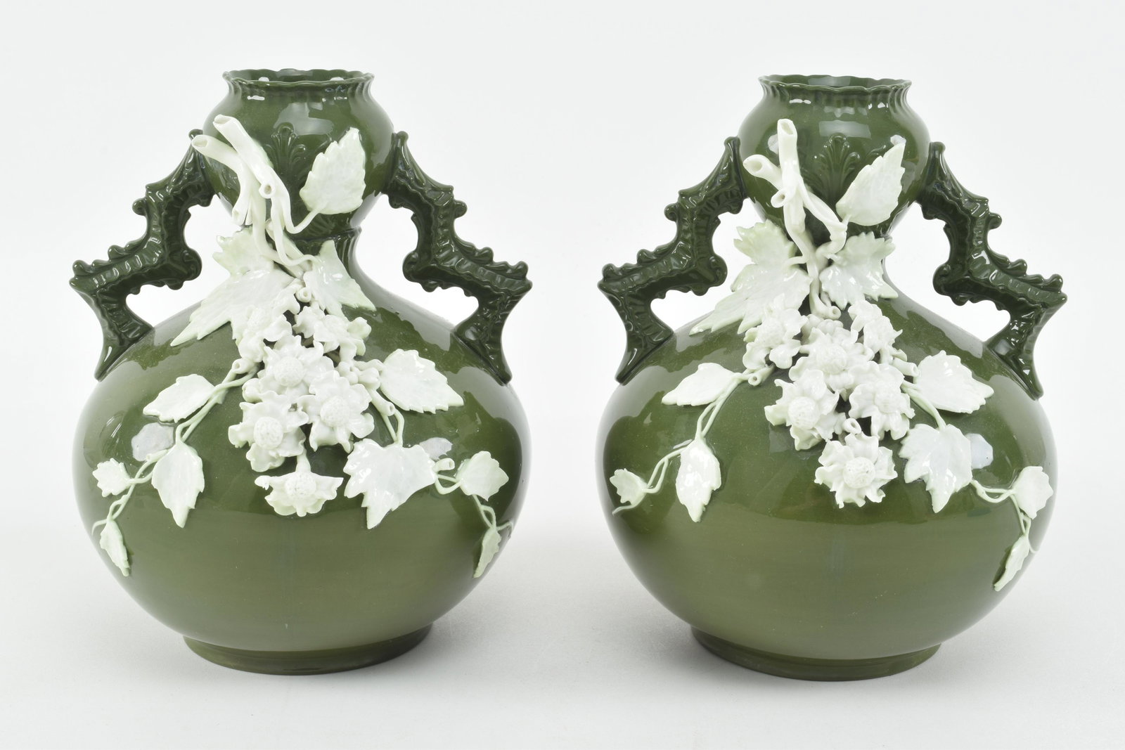 "Lotus Ware" porcelain by Knowles, Taylor and Knowles.: "Lotus Ware" porcelain by Knowles, Taylor and Knowles. Rare pair of green ground porcelain vases with white relief floral decorated vines. Branch style handles. Marked on bases with Lotus ware mark. V