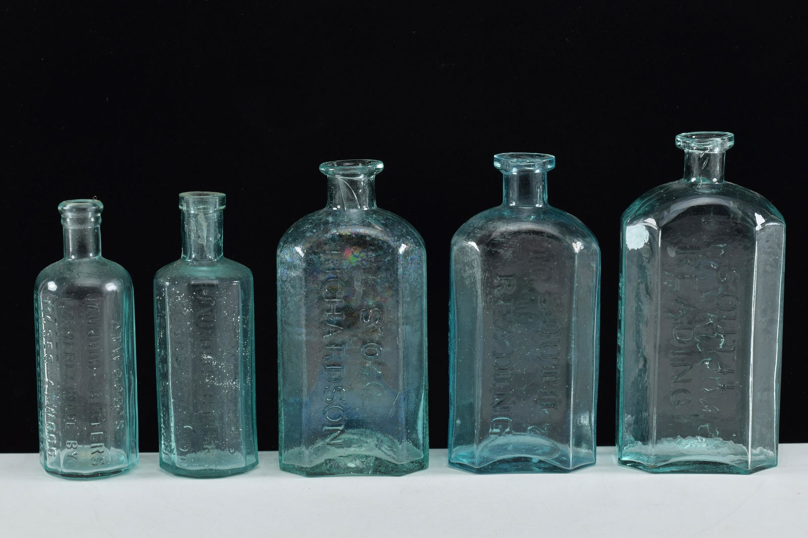 Five antique aqua glass Bitters bottles. (1) W.L.: Five antique aqua glass Bitters bottles. (1) W.L. Richardson. South Reading, Mass. 7-1/2" high. (2) Two S.O. Richardson bottles. One cracked at base. (3) TWo Moses Atwood bottles, Georgetown, Mass. Ta