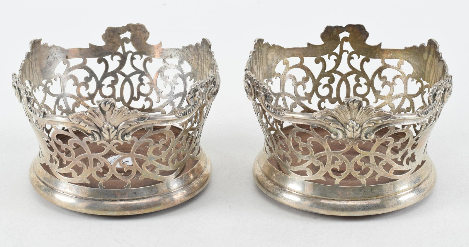 Pair of Dominick and Haff sterling wine coasters. Rococo design with scrolled and foliate edge over: Pair of Dominick and Haff sterling wine coasters. Rococo design with scrolled and foliate edge over lattice work on turned wood bases. Diameter 6.5 in, height 3.5 in