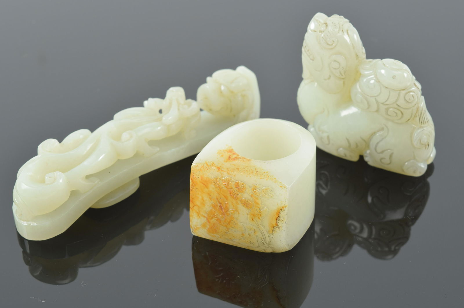 3 jade carvings. China. 19th/20th century. To include: a garment hook, archers ring, and foo dog. (1 of 9)